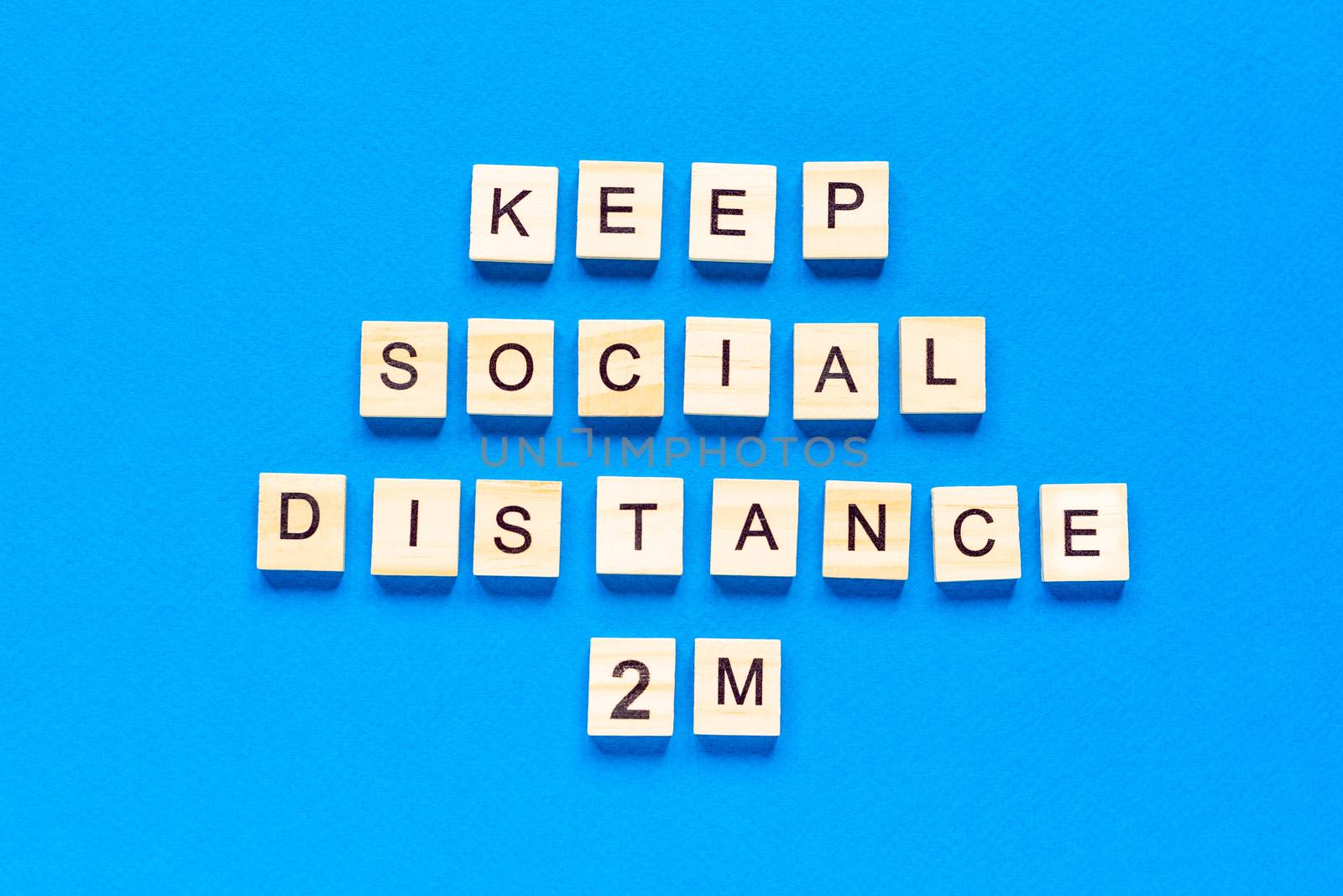 Words keep social distance 2 m. Wooden inscription on a blue background. Information sign of keep social distance 2 m from blocks. flat layout