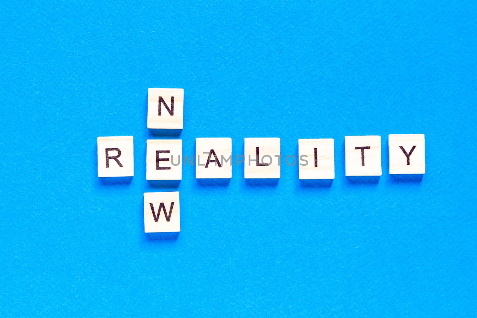 NEW REALITY. the words new reality are written in wooden letters on a blue background. flat layout. top view by Pirlik