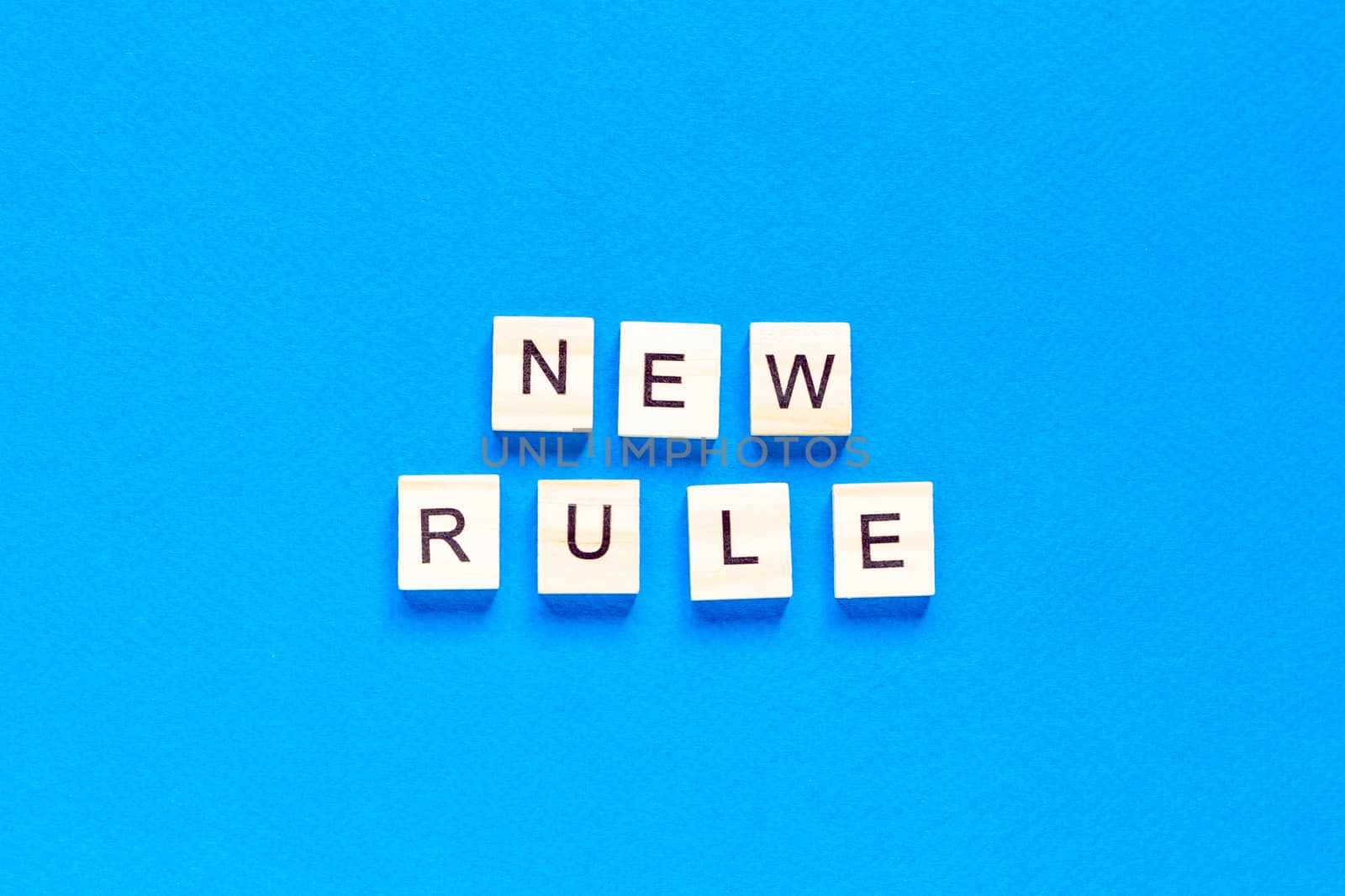 The NEW RULE is written in wooden letters on a blue background. New concept. Business, law, rules, update. tflat layout. op view.