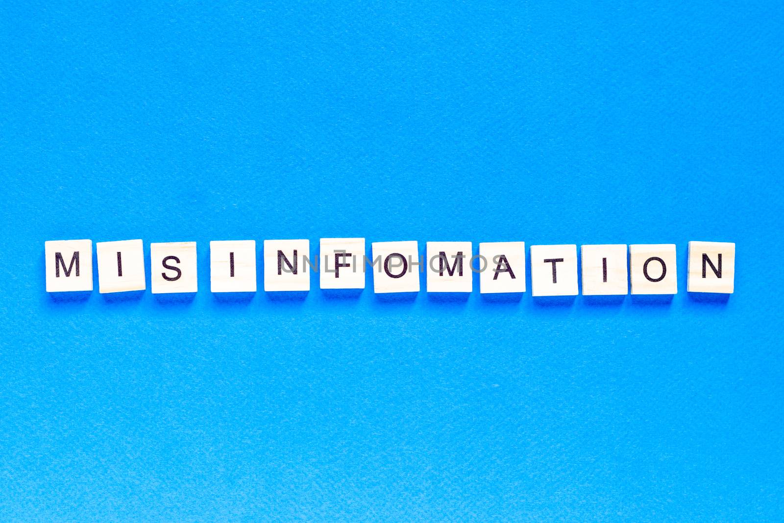 mystification written in wooden letters on a blue background, top view, deception, fake information, fake news, flat layout