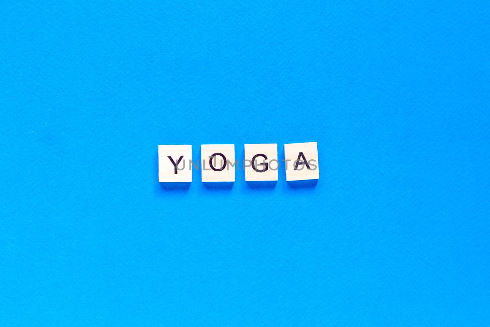 The word YOGA written in wooden letterpress type on a blue background. top view. flat layout.