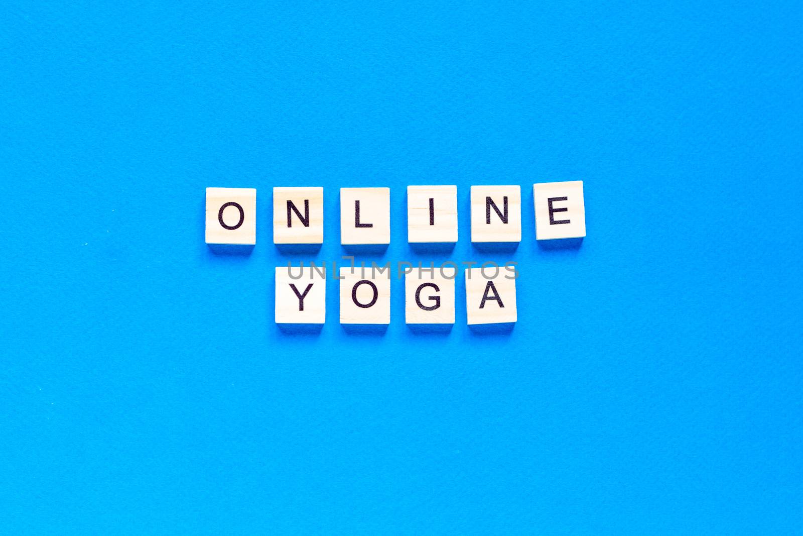 The word ONLINE YOGA written in wooden letterpress type on a blue background. flat layout. top view. by Pirlik