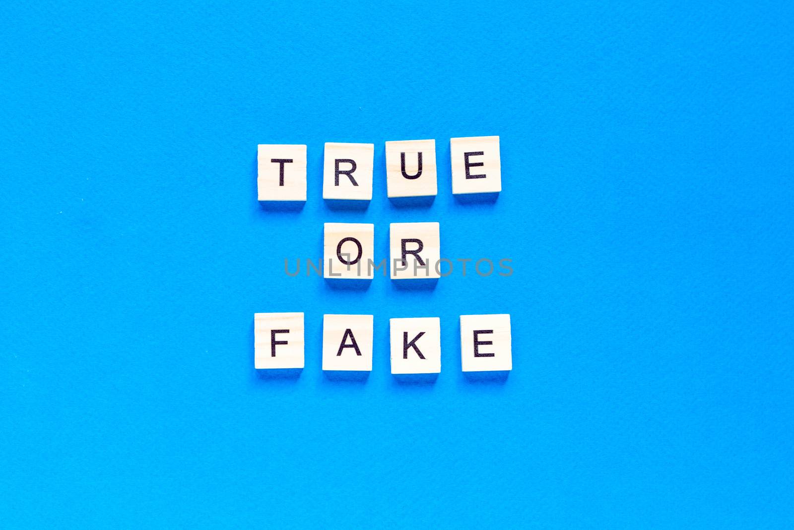 TRUE OR FAKE word alphabet letters on blue background. top view. flat layout. by Pirlik