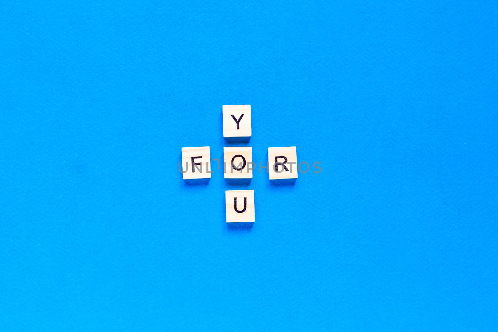 FOR YOU written in wooden letters on a blue background. top view, flat layout.