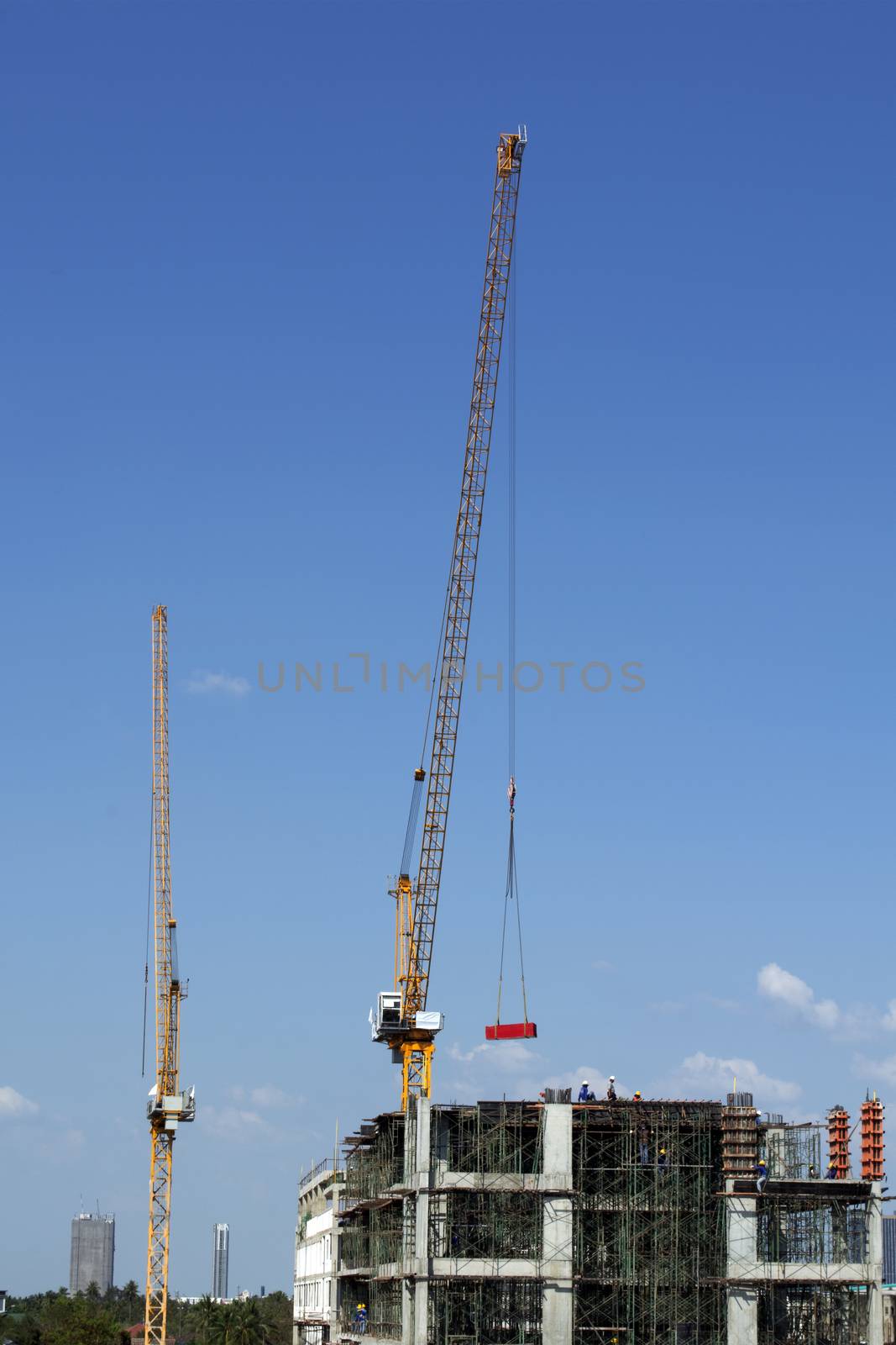Crane lifting material for building construction on bright blue  by pandpstock_002
