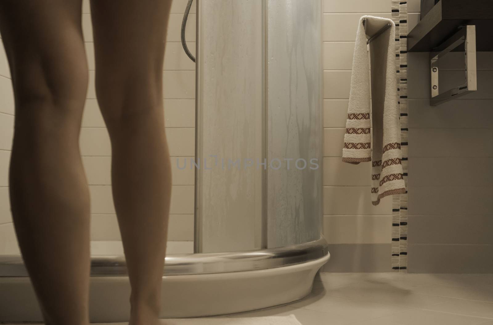 Sexy naked woman's legs entering the foggy glass shower cabin in her modern design bathroom by robbyfontanesi