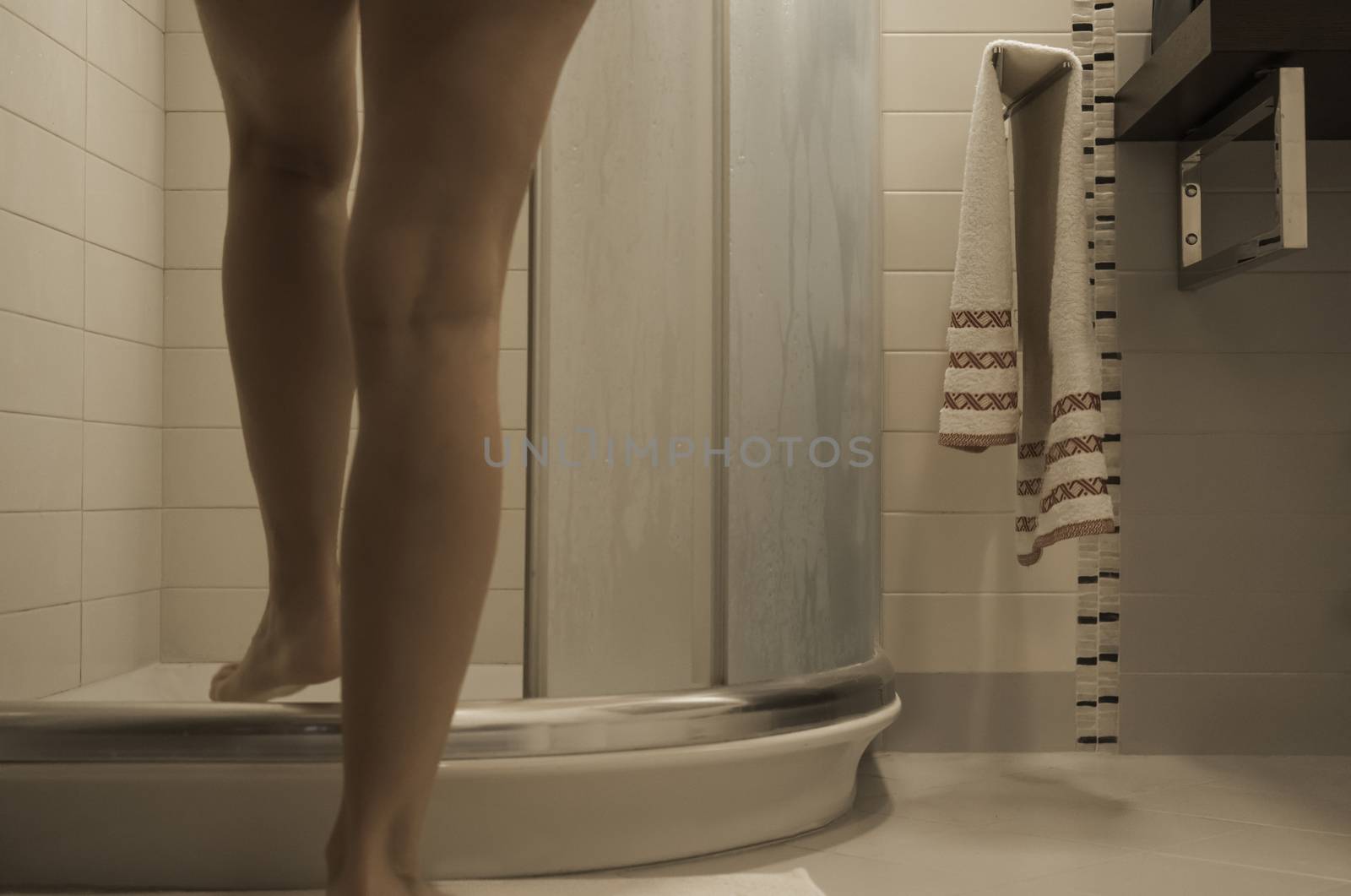 Sexy naked woman's legs entering the foggy glass shower cabin in her modern design bathroom by robbyfontanesi