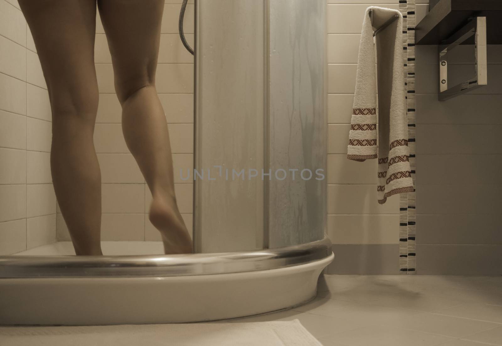 Sexy naked woman's legs entering the foggy glass shower cabin in her modern design bathroom by robbyfontanesi