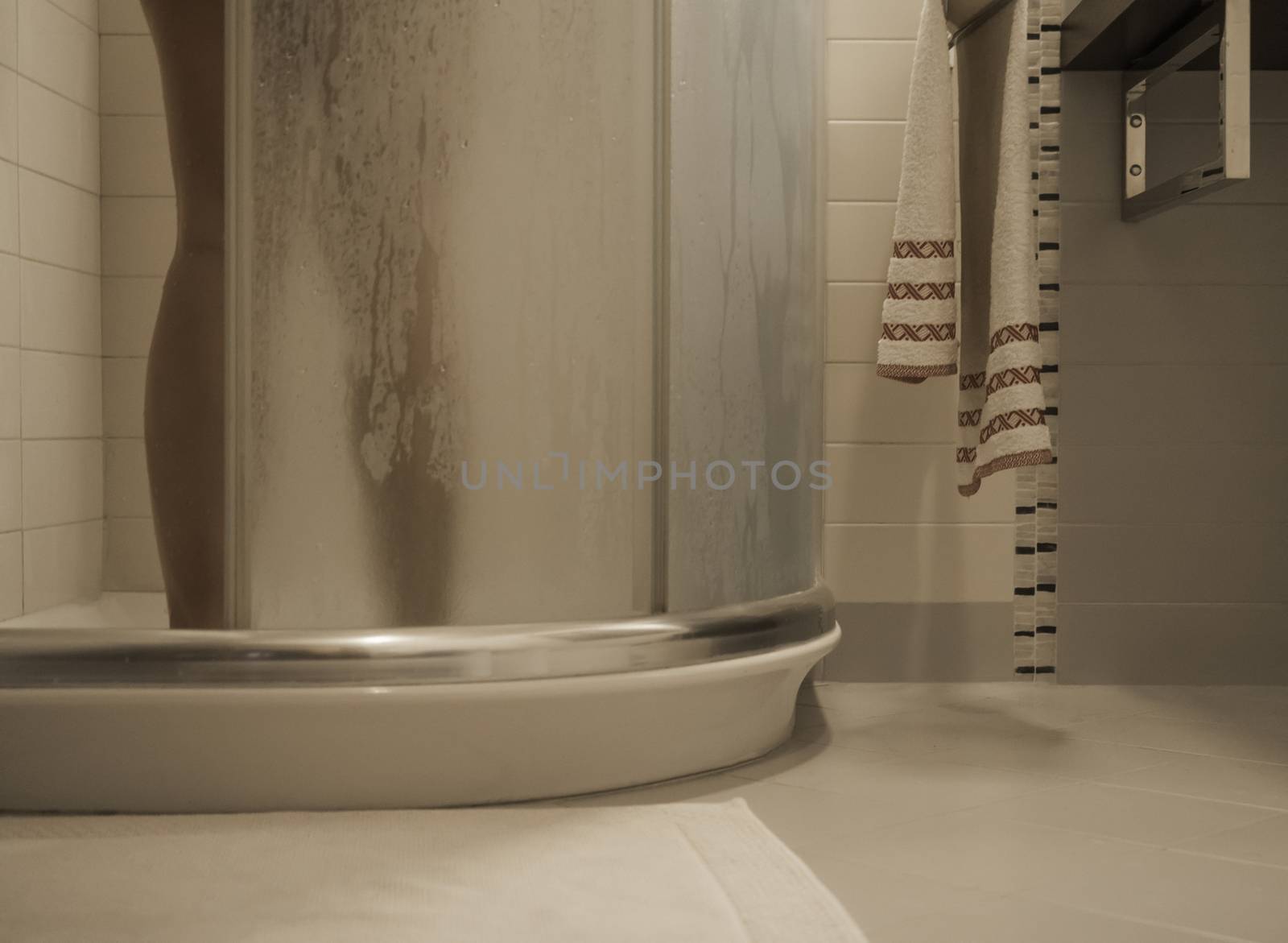 Sexy naked woman's legs inside the shower cabin closes the fogged glass door in her modern design bathroom by robbyfontanesi