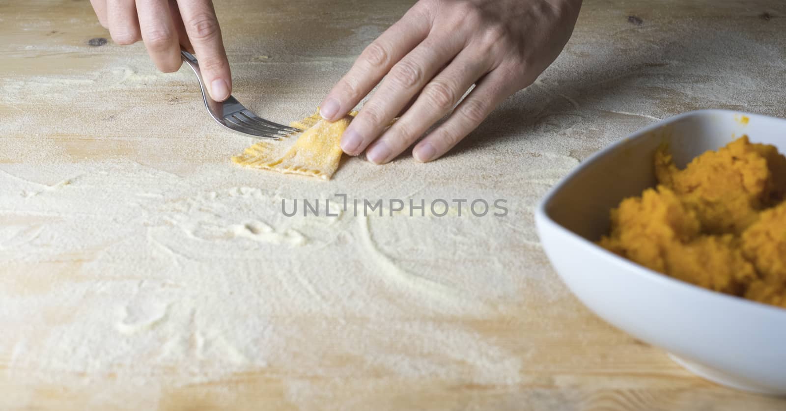 Closeup process making ravioli vegan homemade pasta. Housewife cook closes with a fork 'tortelli di zucca', traditional italian pasta, woman cooking food on kitchen by robbyfontanesi