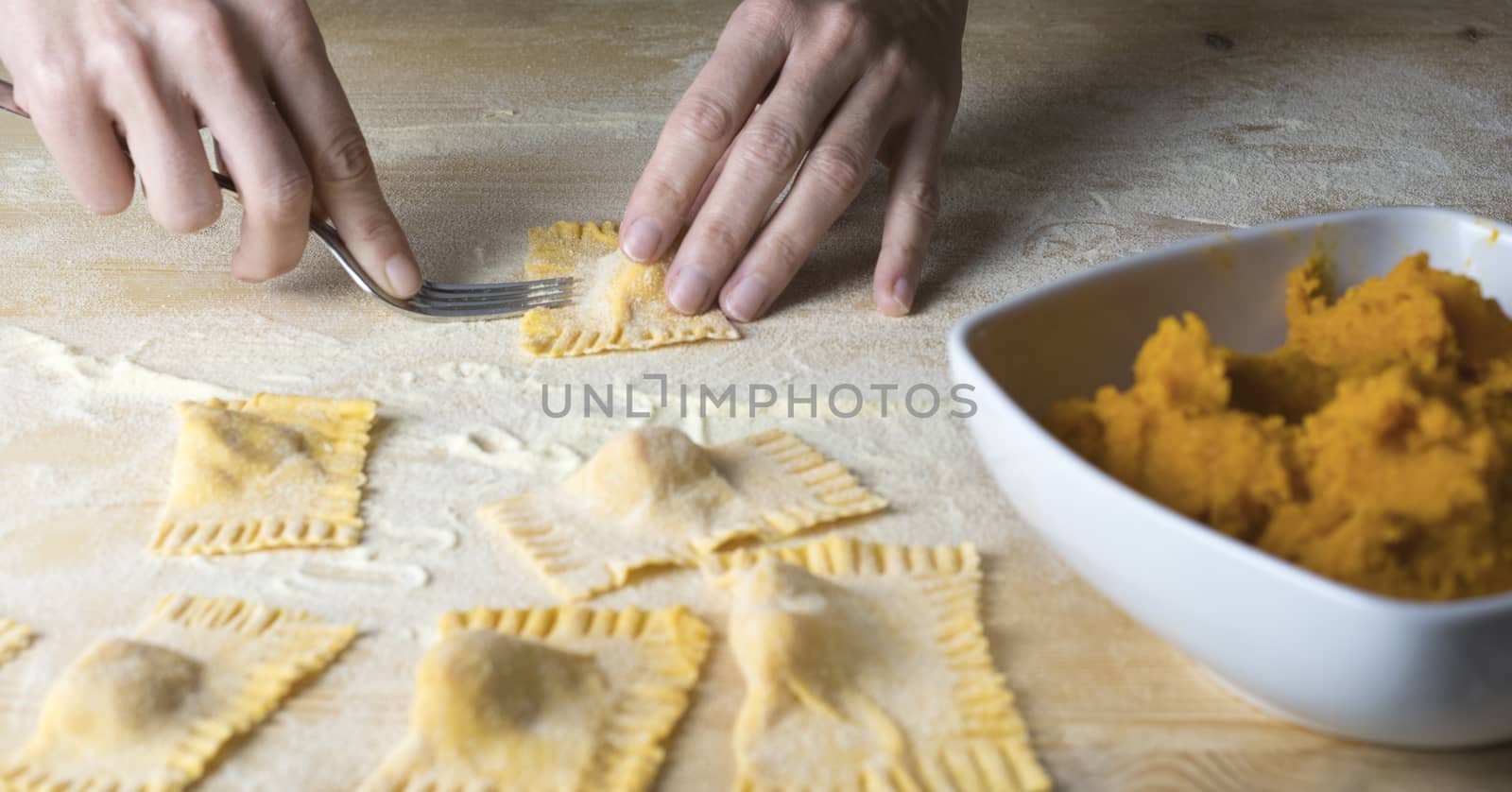 Closeup process making ravioli vegan homemade pasta. Housewife cook closes with a fork 'tortelli di zucca', traditional italian pasta, woman cooking food on kitchen by robbyfontanesi