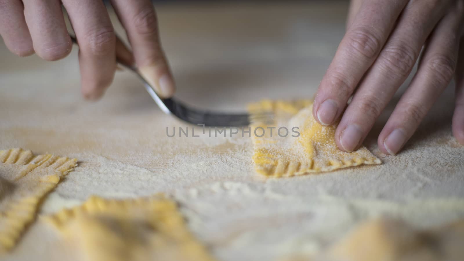 Closeup process making ravioli vegan homemade pasta. Housewife cook closes with a fork 'tortelli di zucca', traditional italian pasta, woman cooking food on kitchen by robbyfontanesi
