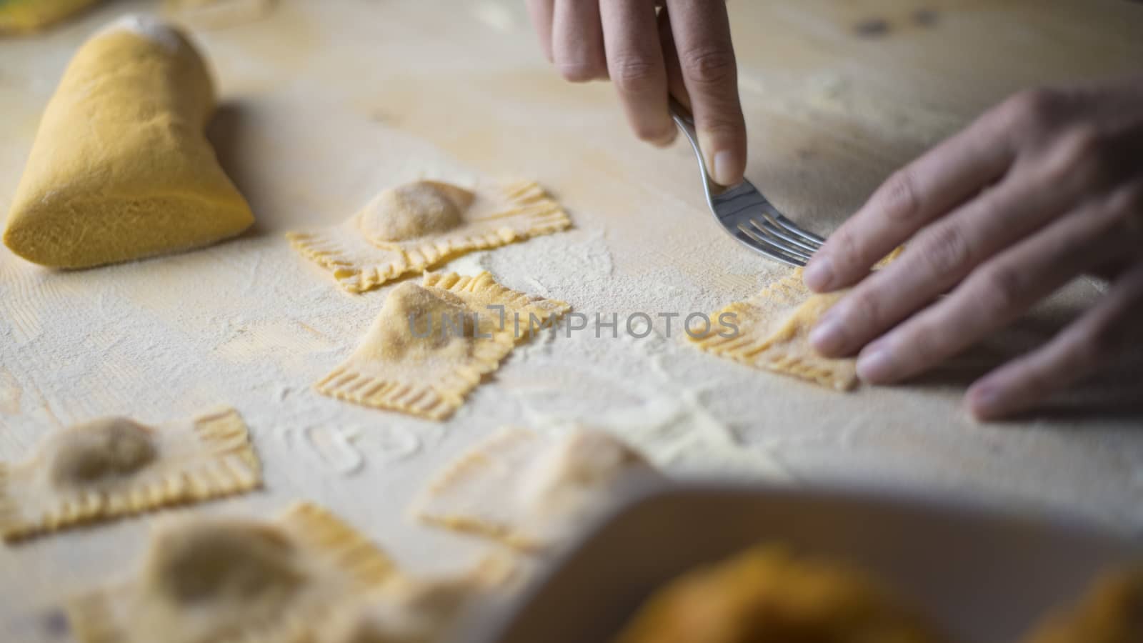 Closeup process making ravioli vegan homemade pasta. Housewife cook closes with a fork 'tortelli di zucca', traditional italian pasta, woman cooking food on kitchen