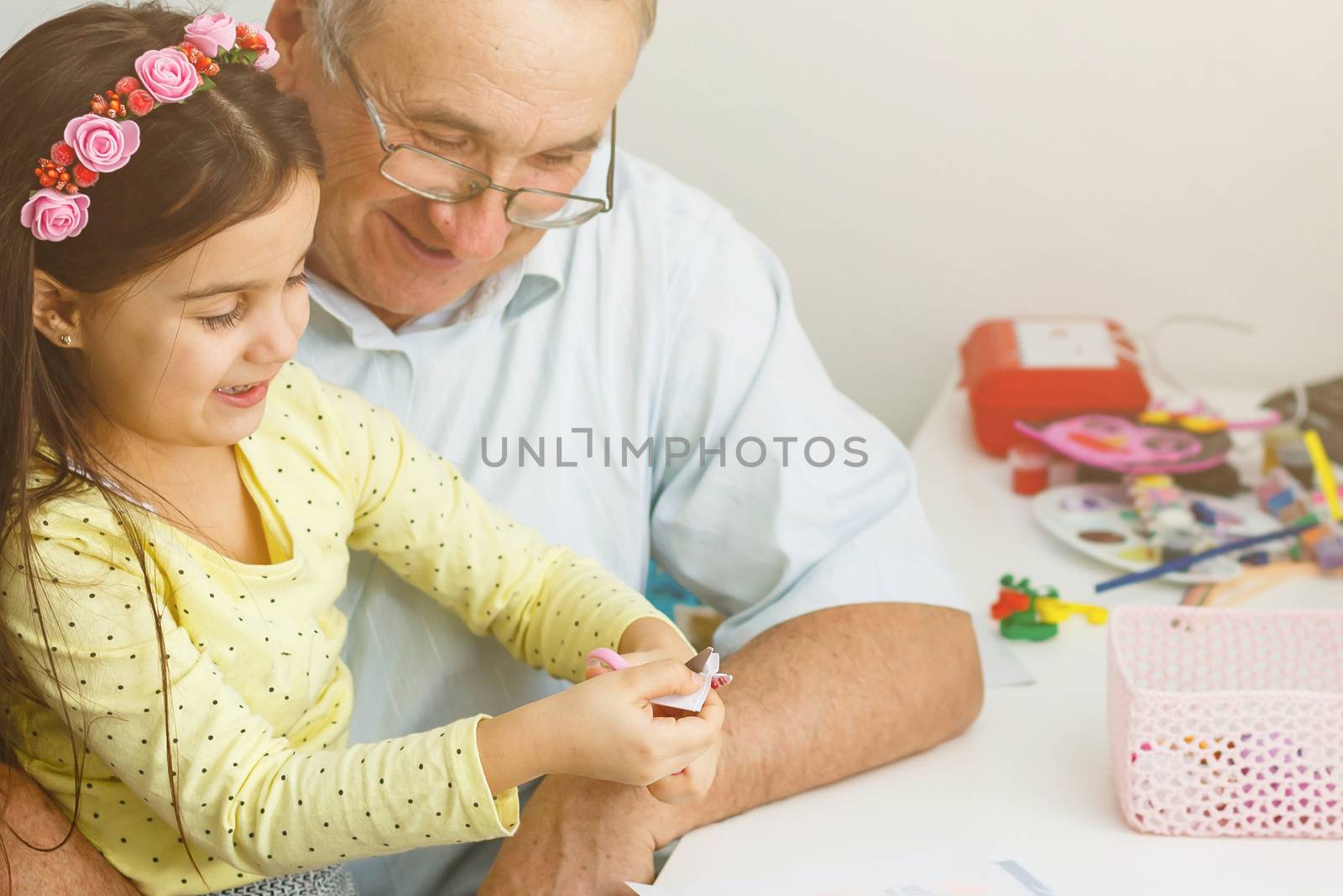 Caring grandfather doing home assignment together with granddaughter by Andelov13