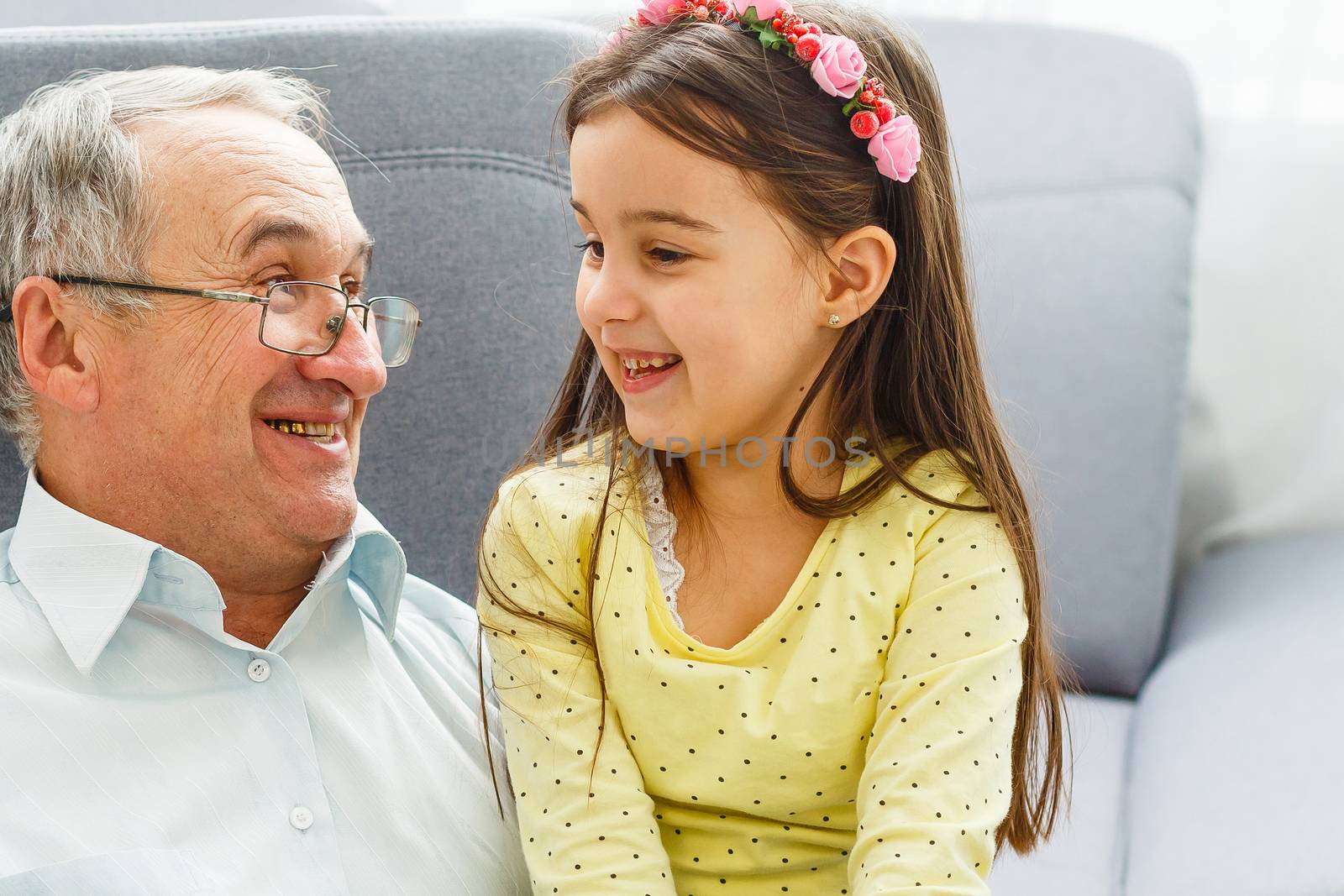 Granddaughter and grandfather watching photos together in a photo album at home by Andelov13