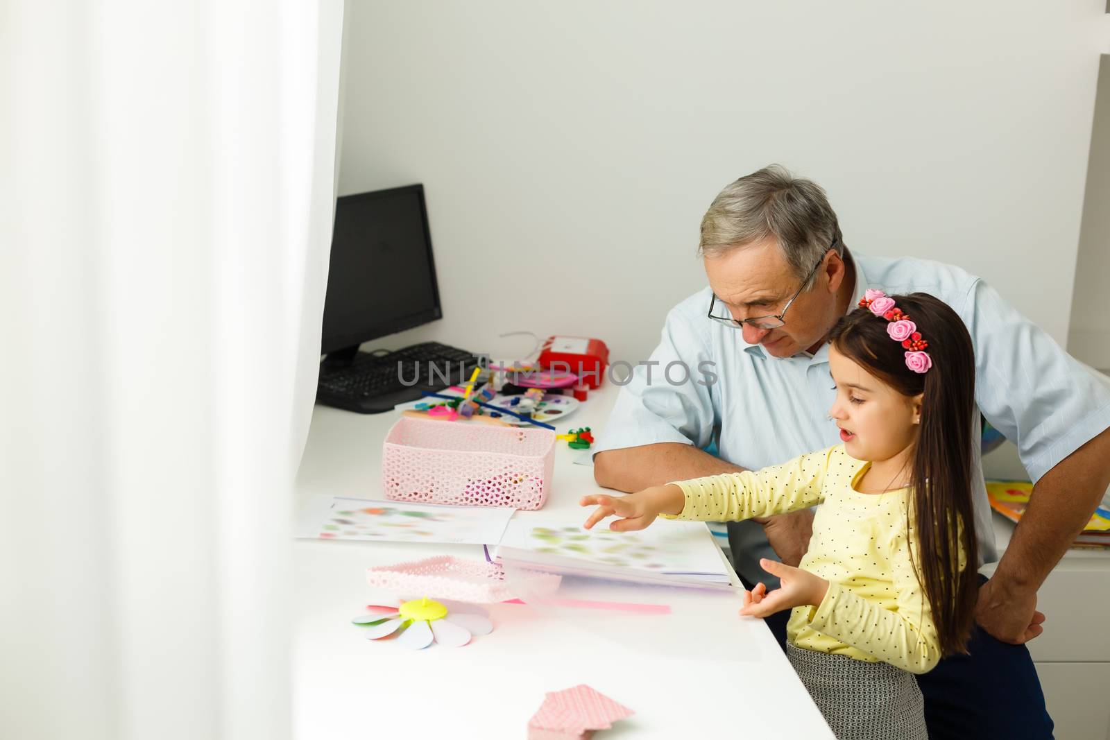 Caring grandfather doing home assignment together with granddaughter