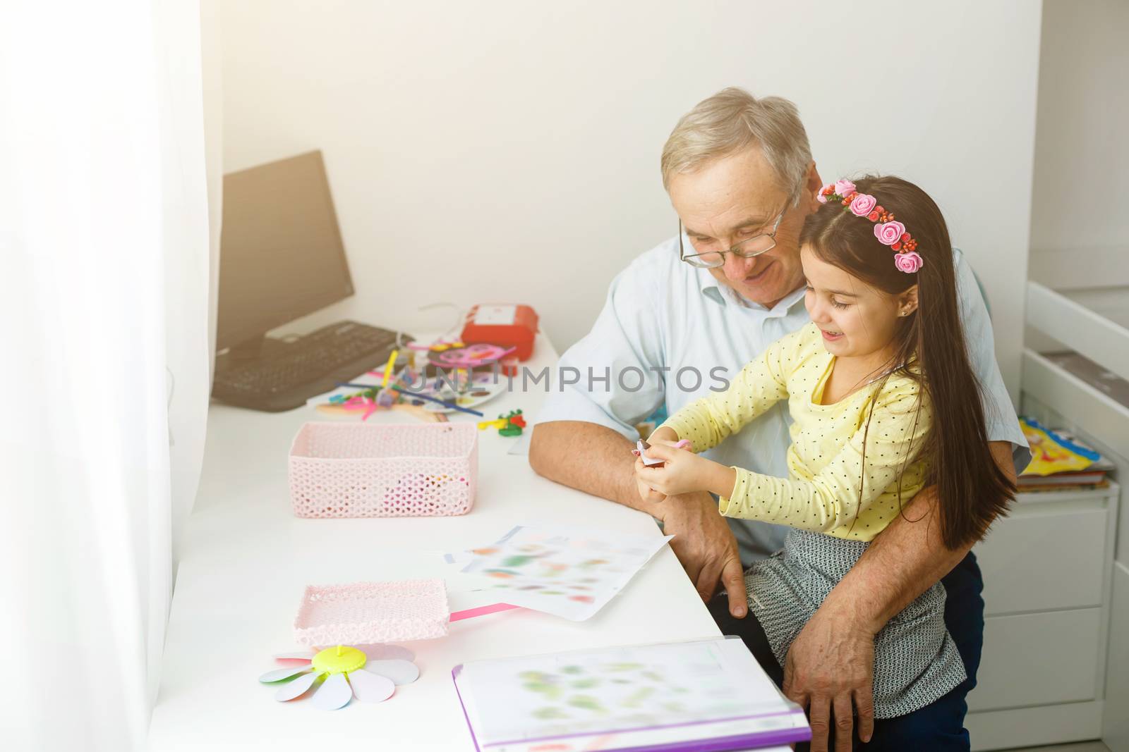 Caring grandfather doing home assignment together with granddaughter by Andelov13