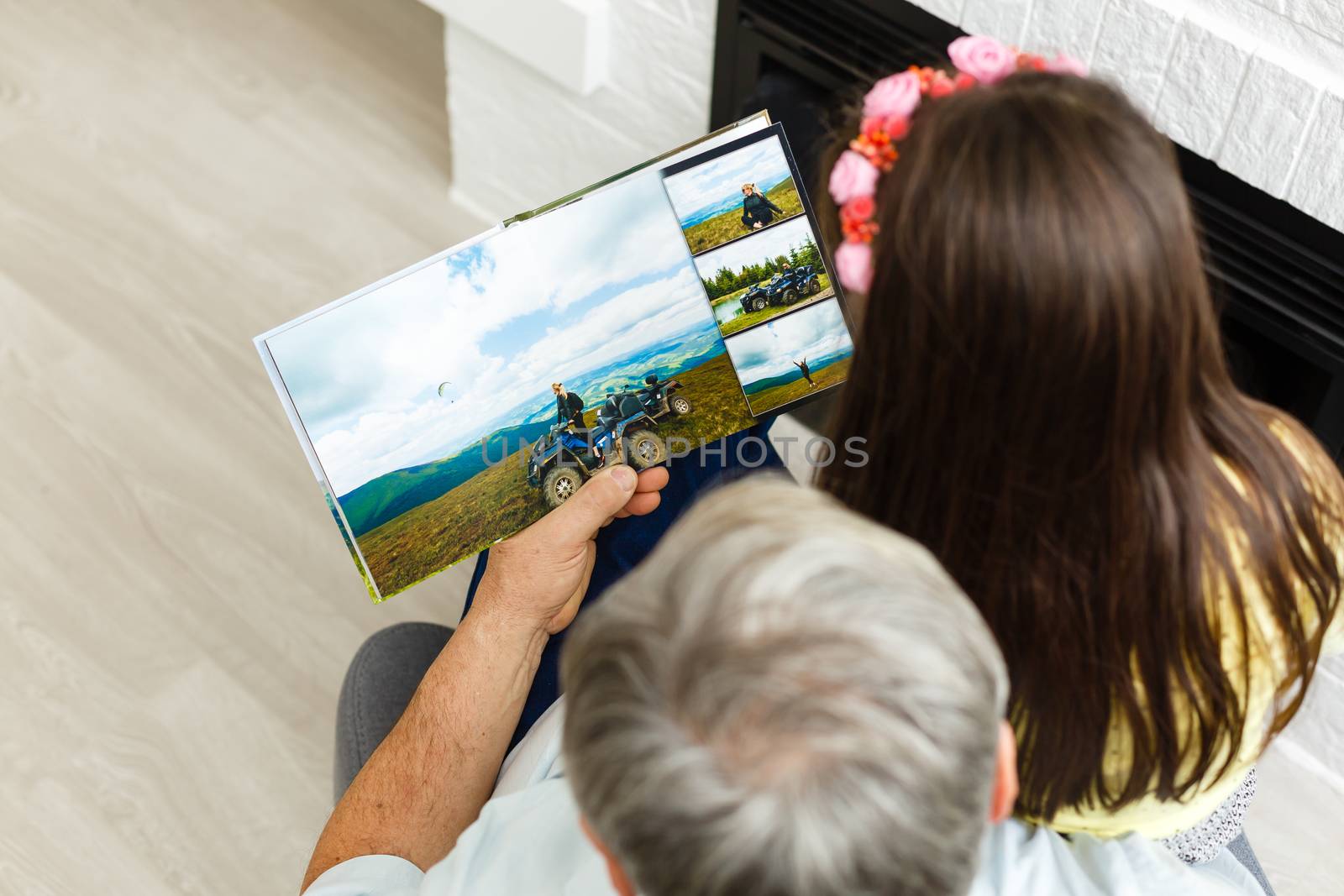 Granddaughter and grandfather watching photos together in a photo album at home