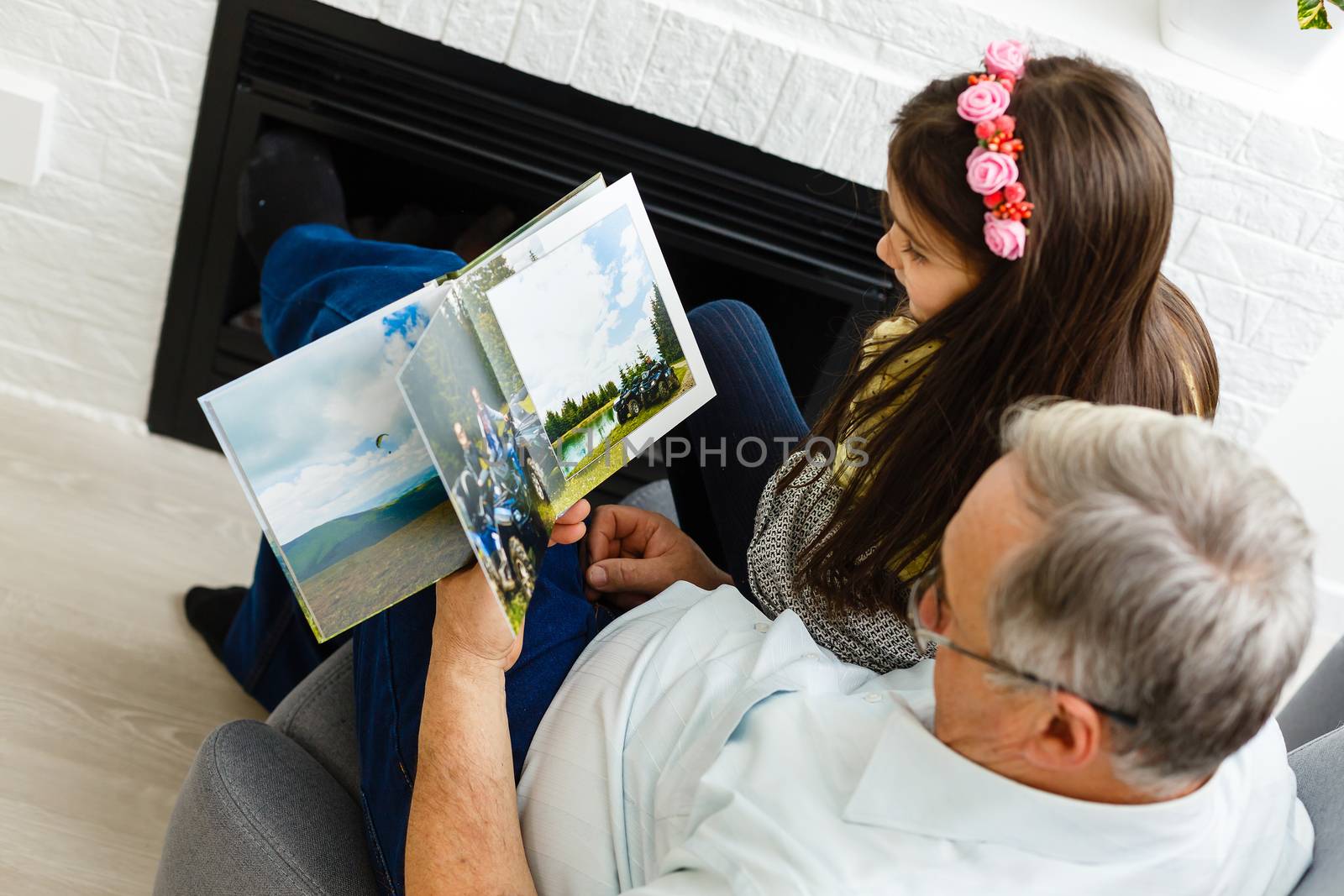 Granddaughter and grandfather watching photos together in a photo album at home