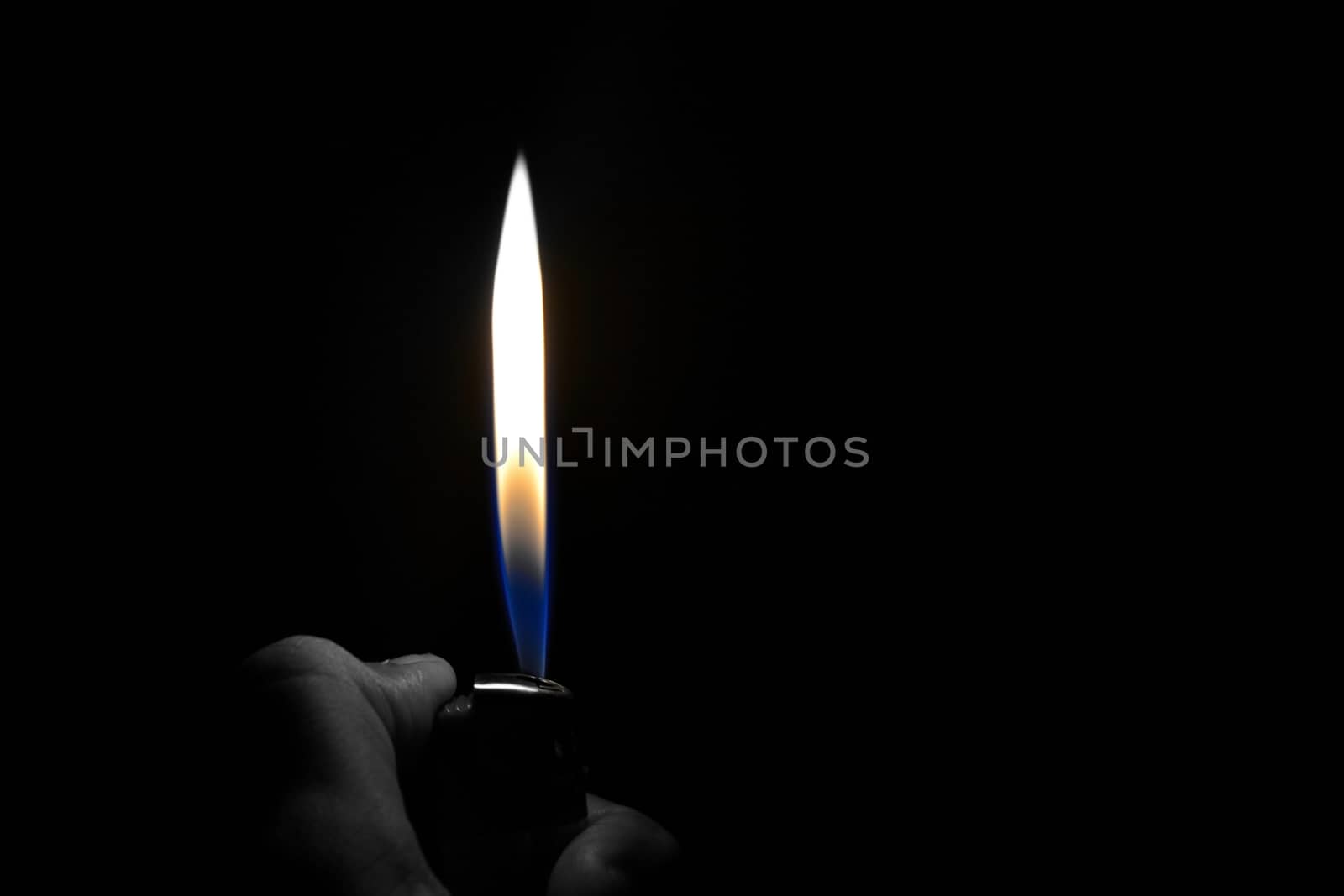 A hand lighting up a lighter with flame and dark background