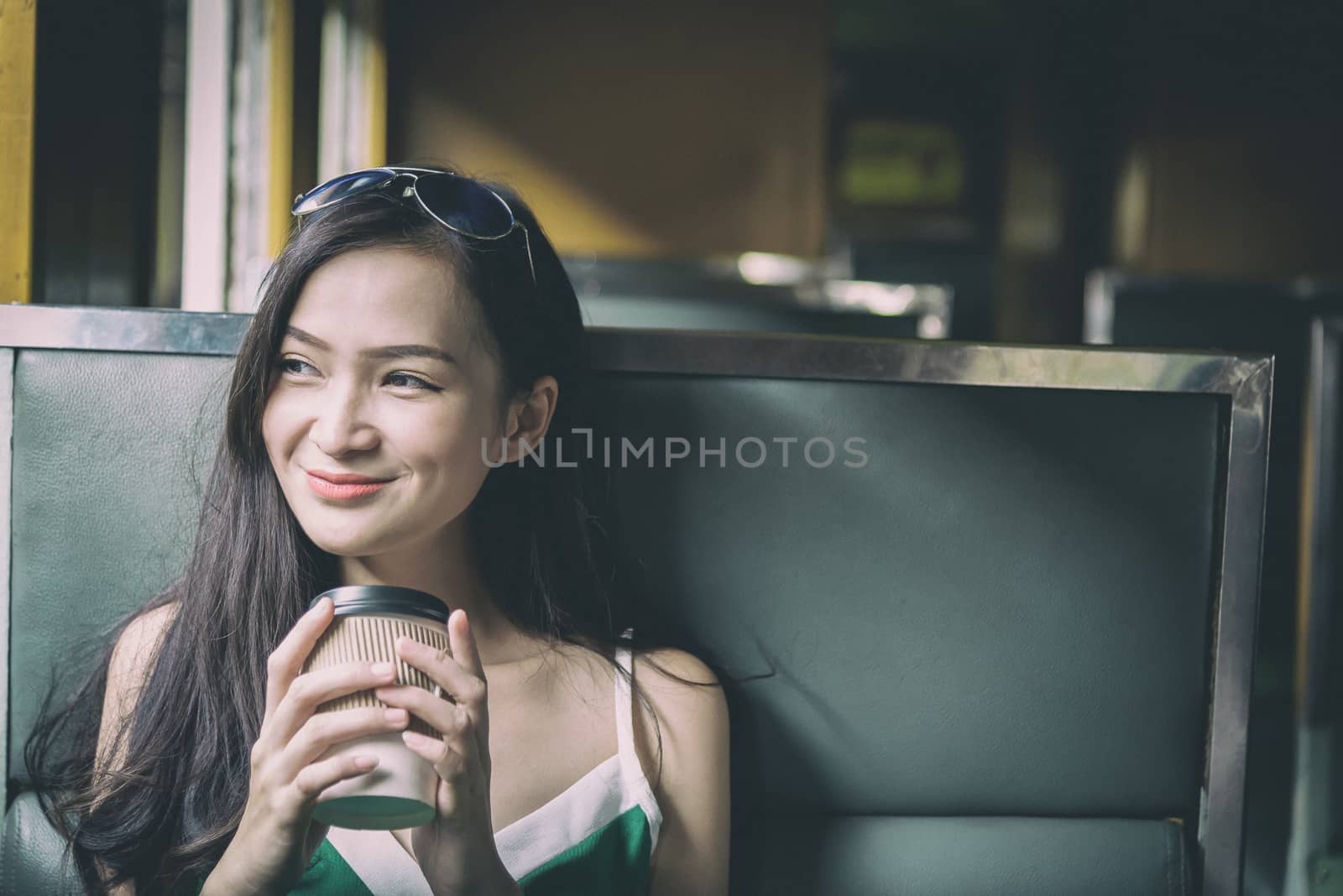 Asian woman traveler has drinking coffee in the train with happiness at Hua Lamphong station at Bangkok, Thailand.