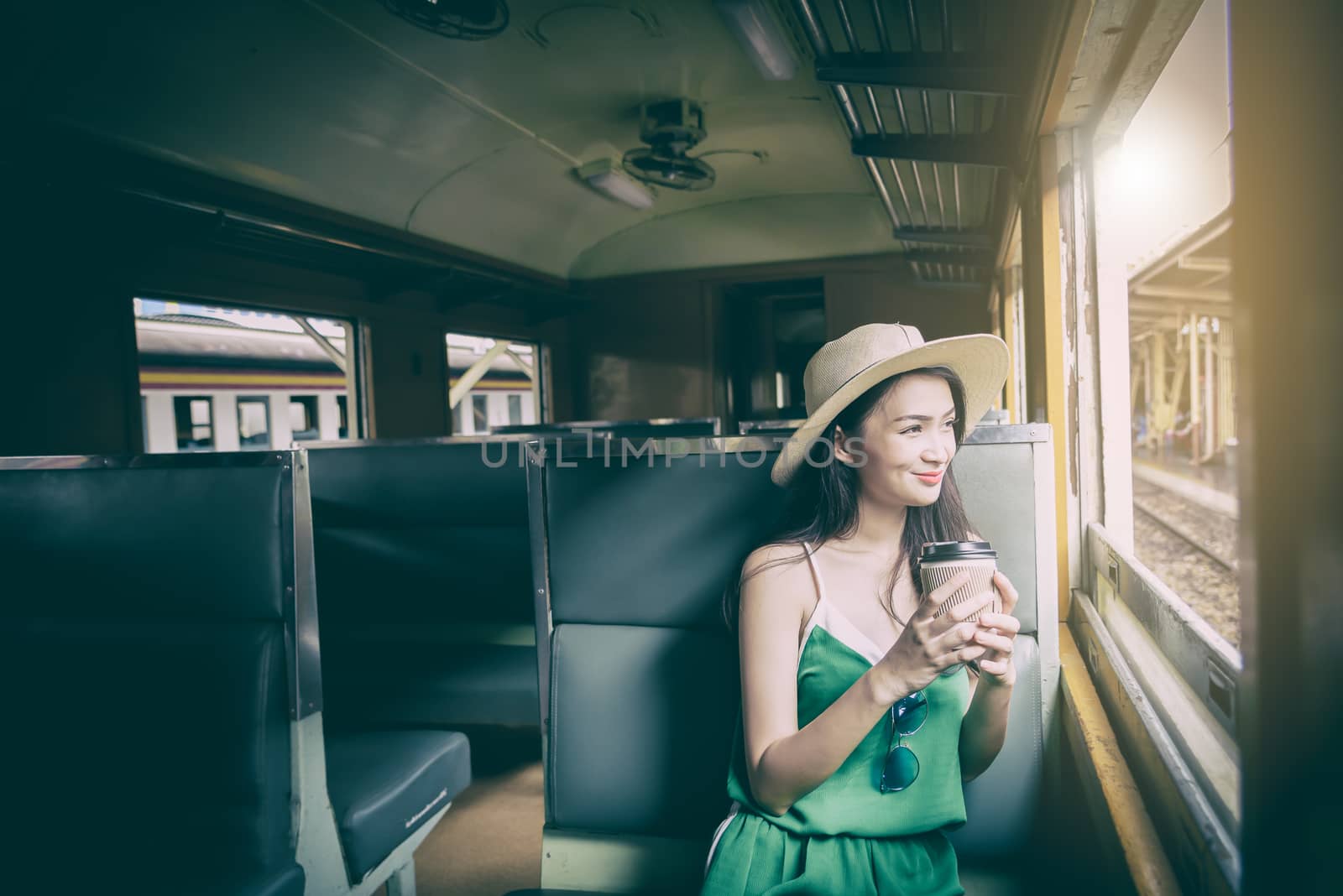 Asian woman traveler has drinking coffee in the train with happiness at Hua Lamphong station at Bangkok, Thailand.