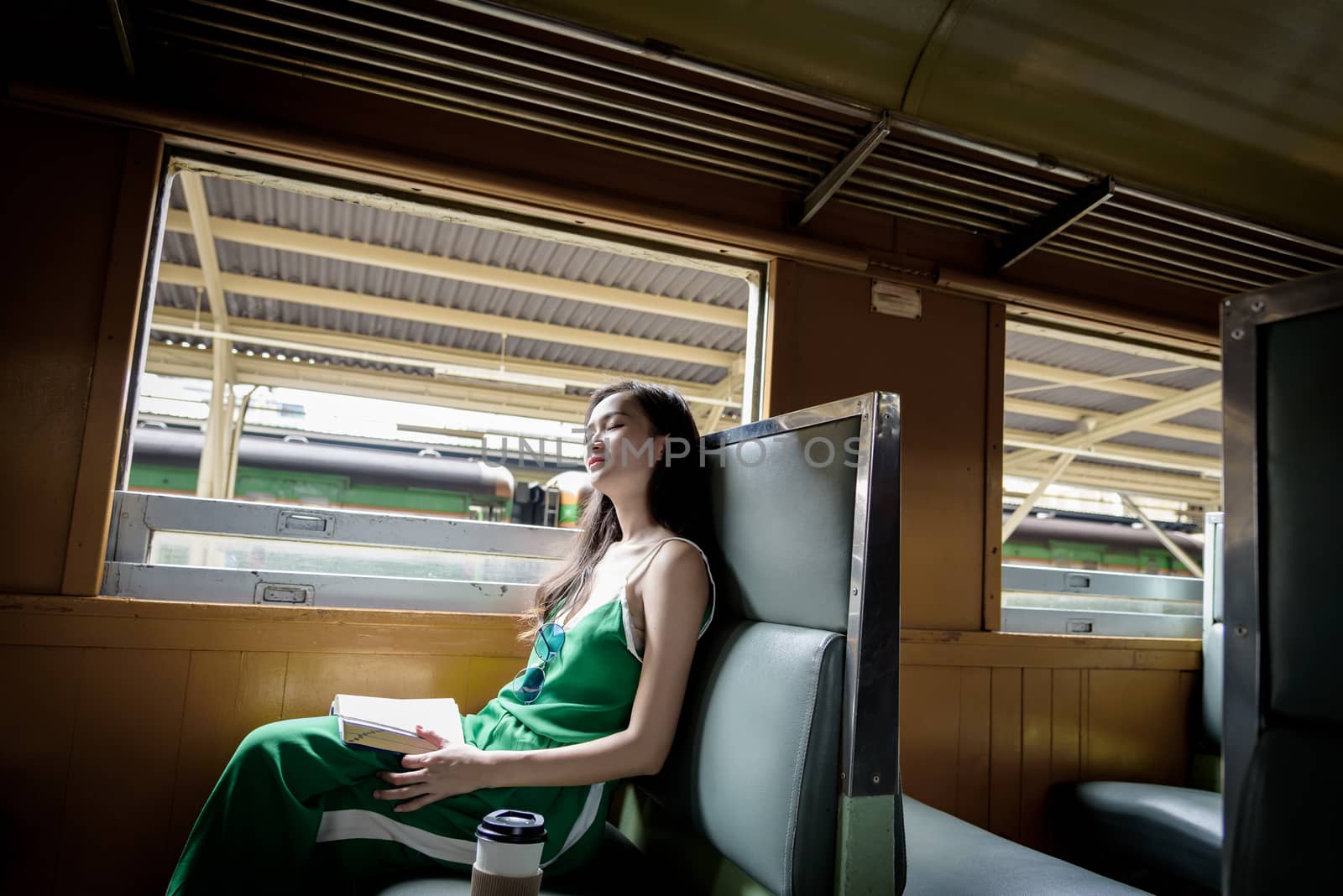 Asian woman traveler has sleeping in the train with happiness at Hua Lamphong station at Bangkok, Thailand.