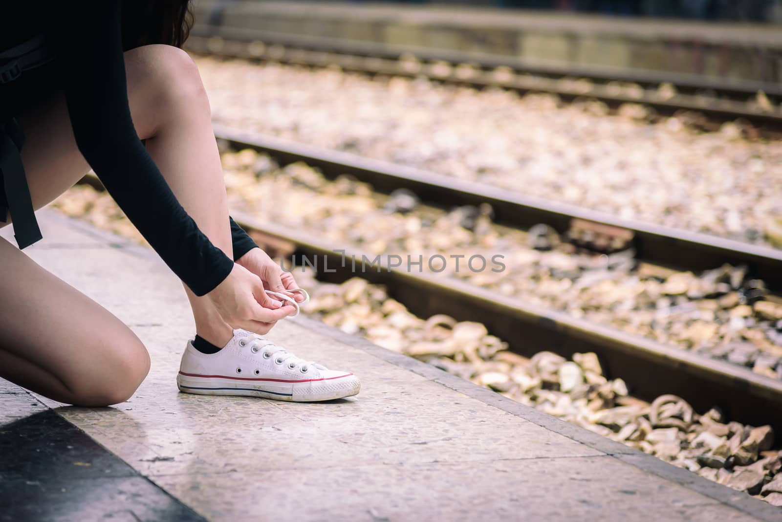 Asian woman traveler has tying shoe laces for traveling by train at Hua Lamphong station at Bangkok, Thailand.