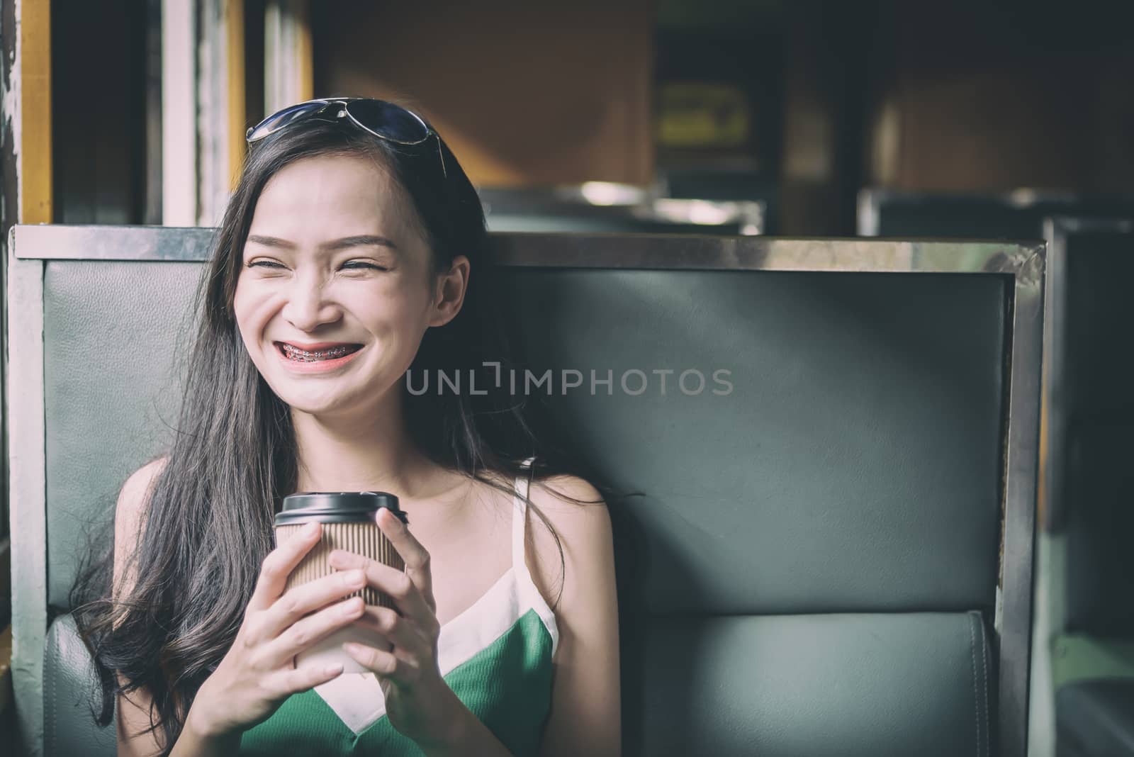 Asian woman traveler has drinking coffee in the train with happiness at Hua Lamphong station at Bangkok, Thailand.