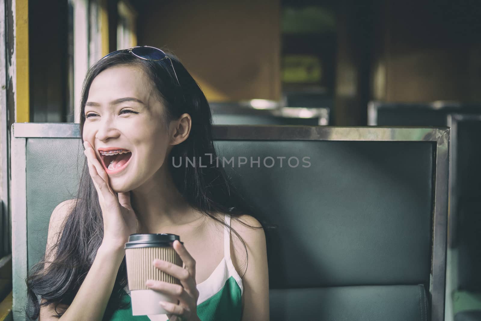 Asian woman traveler has drinking coffee in the train with happi by animagesdesign