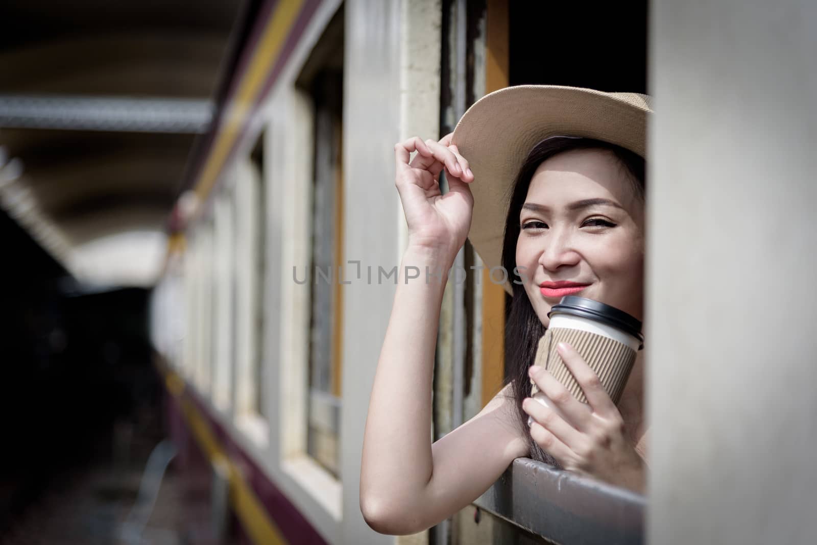 Asian woman traveler has drinking coffee in the train with happiness at Hua Lamphong station at Bangkok, Thailand.