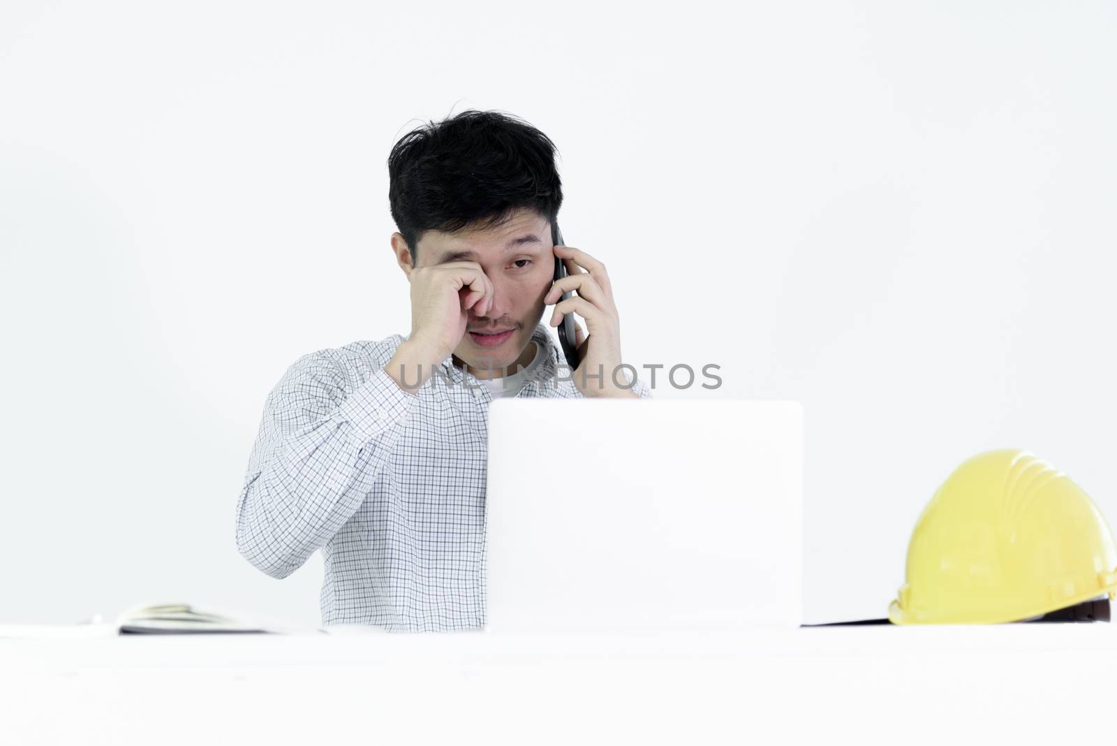 Asian employee engineer salary man sitting at desk and talking with phone and feeling sleepy, isolated on white background.