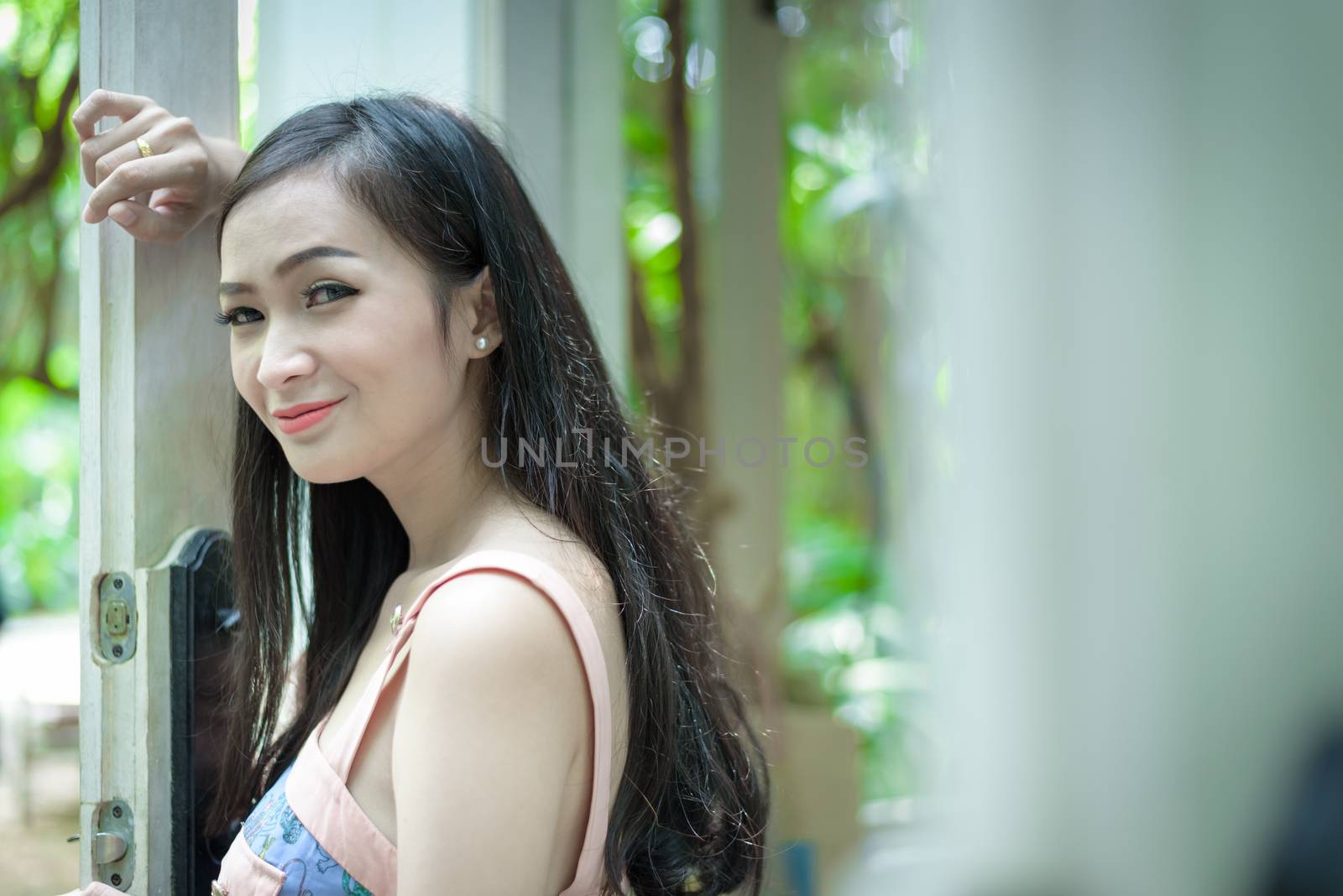 Asian pretty girl has opening the door with happy and smiling at Little Tree Garden cafe, Nakhon Pathom province, Thailand in the morning.