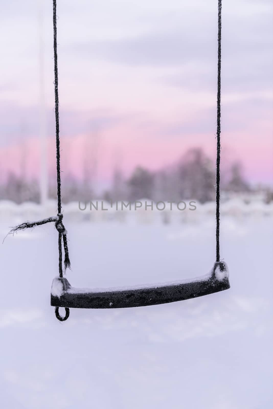 The swing has covered with heavy snow and sunset time in winter season at Holiday Village Kuukiuru, Finland.