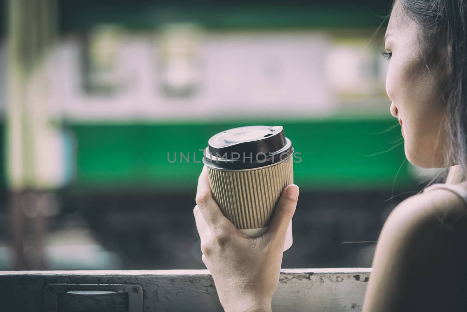 Asian woman traveler has drinking coffee in the train with happiness at Hua Lamphong station at Bangkok, Thailand.