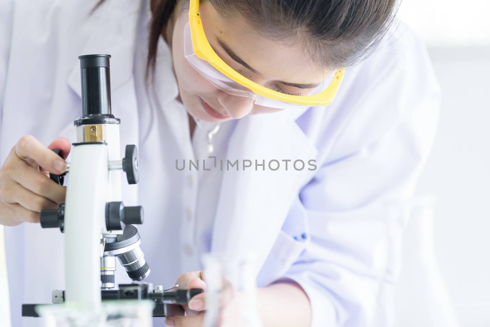 Asian young student scientist researching with a microscope in a laboratory.