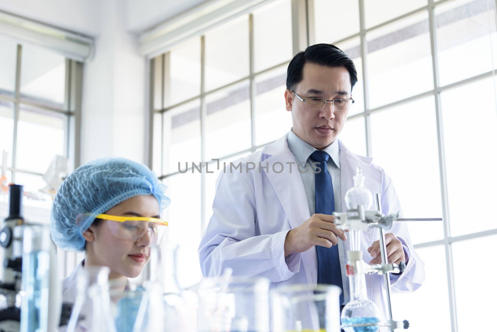 Asian senior scientist have teaching young student scientist in a laboratory.