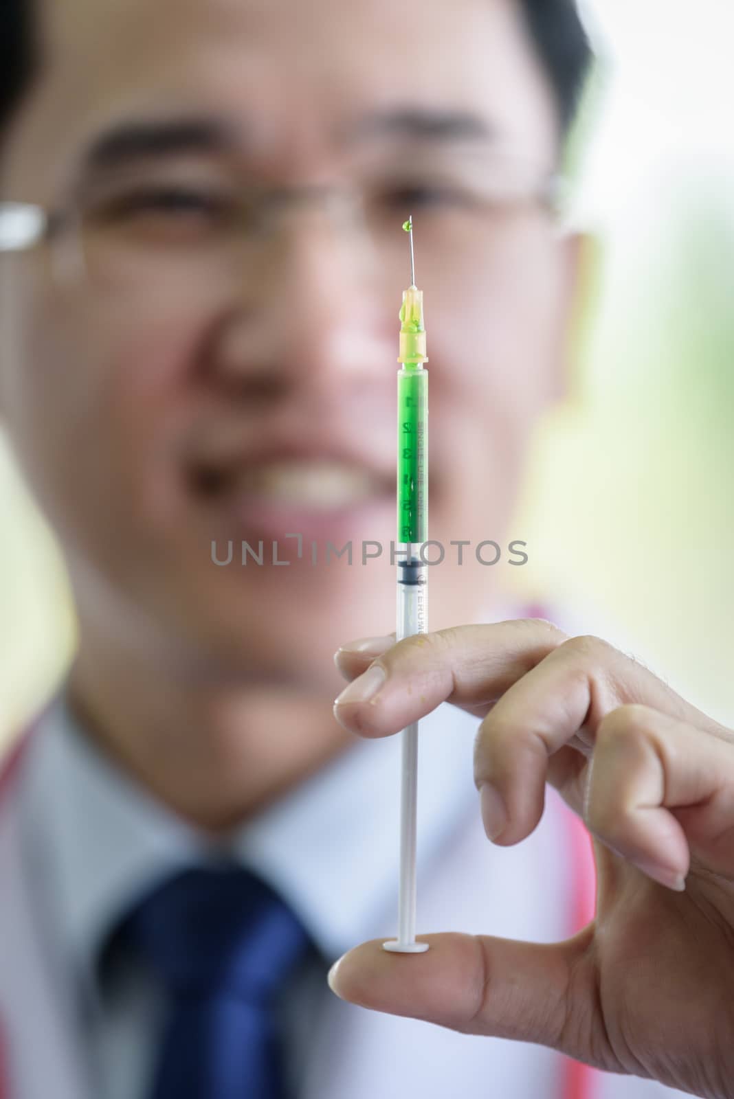 Professional asian doctor with green syringe and splashing.