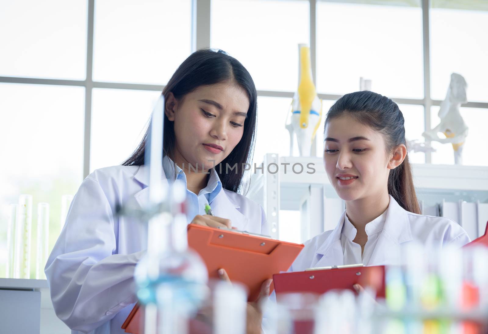Asian young female working and research scientist together. by animagesdesign