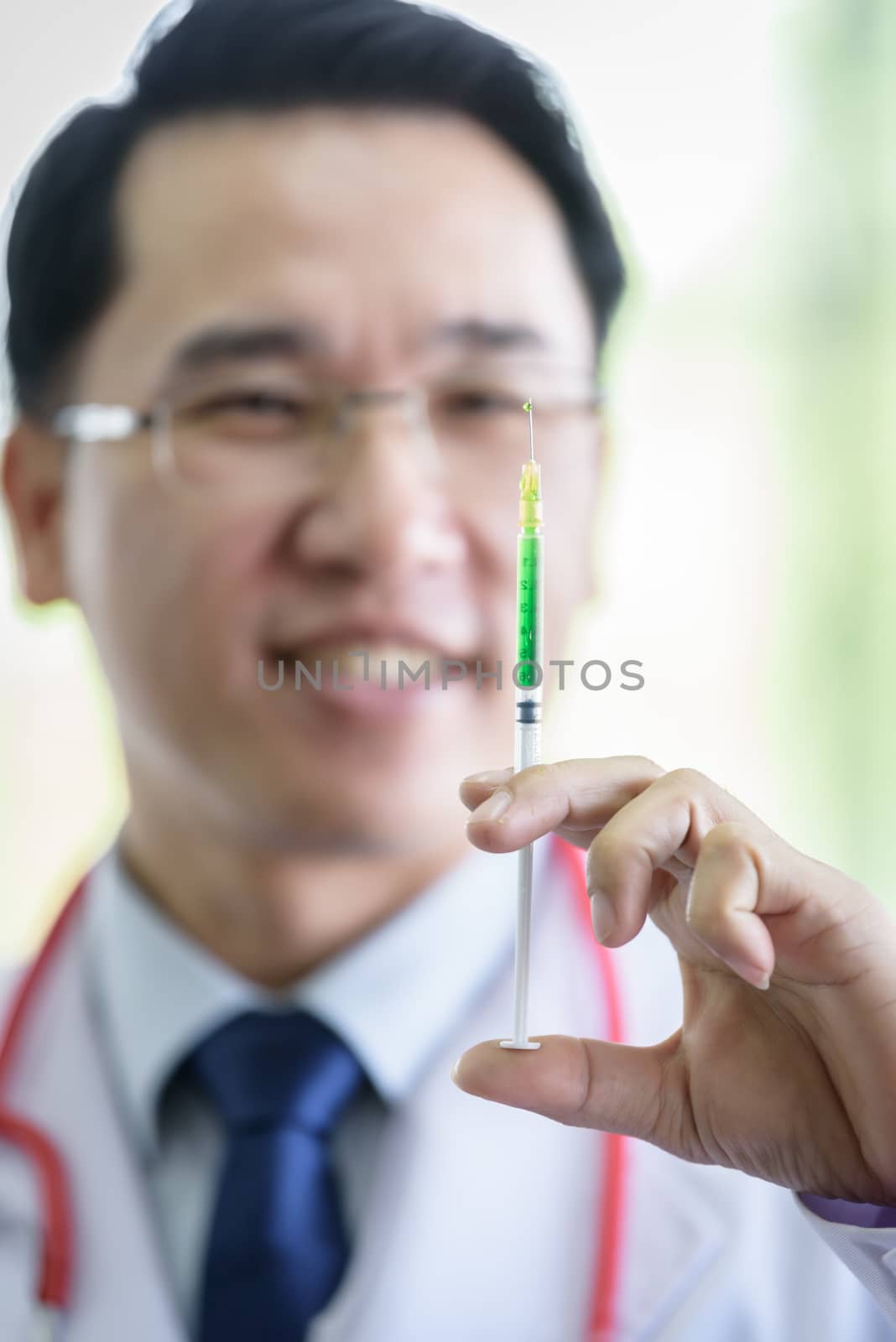 Professional asian doctor with green syringe and splashing.