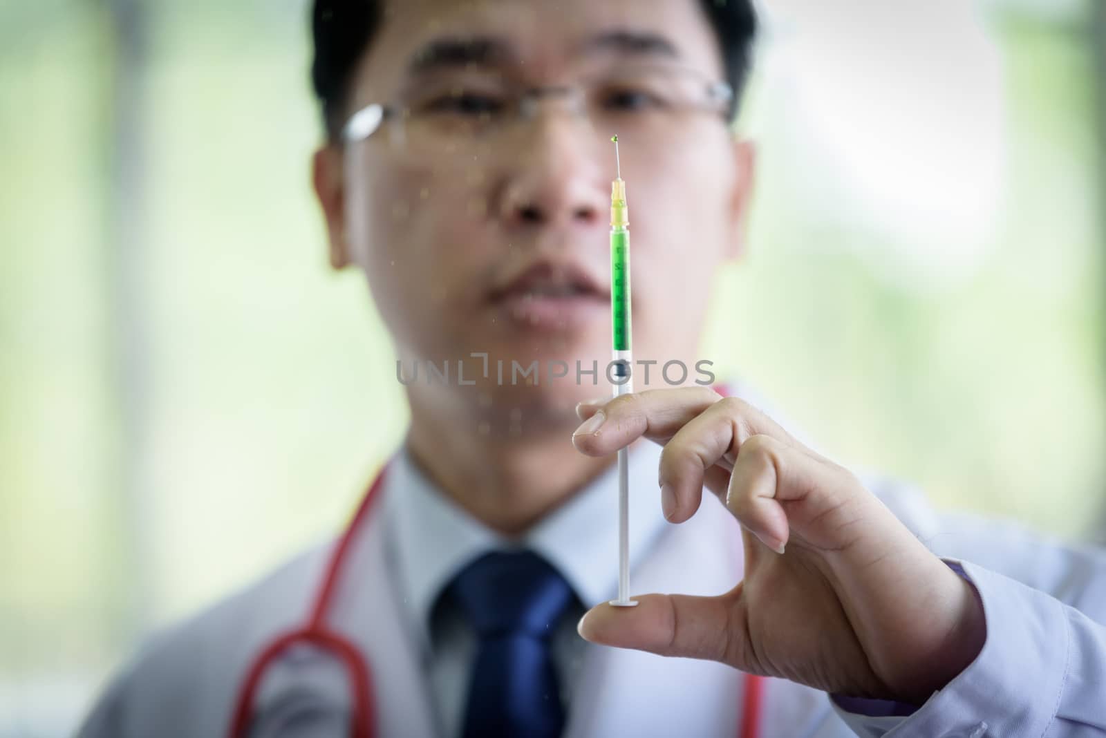 Professional asian doctor with green syringe and splashing.