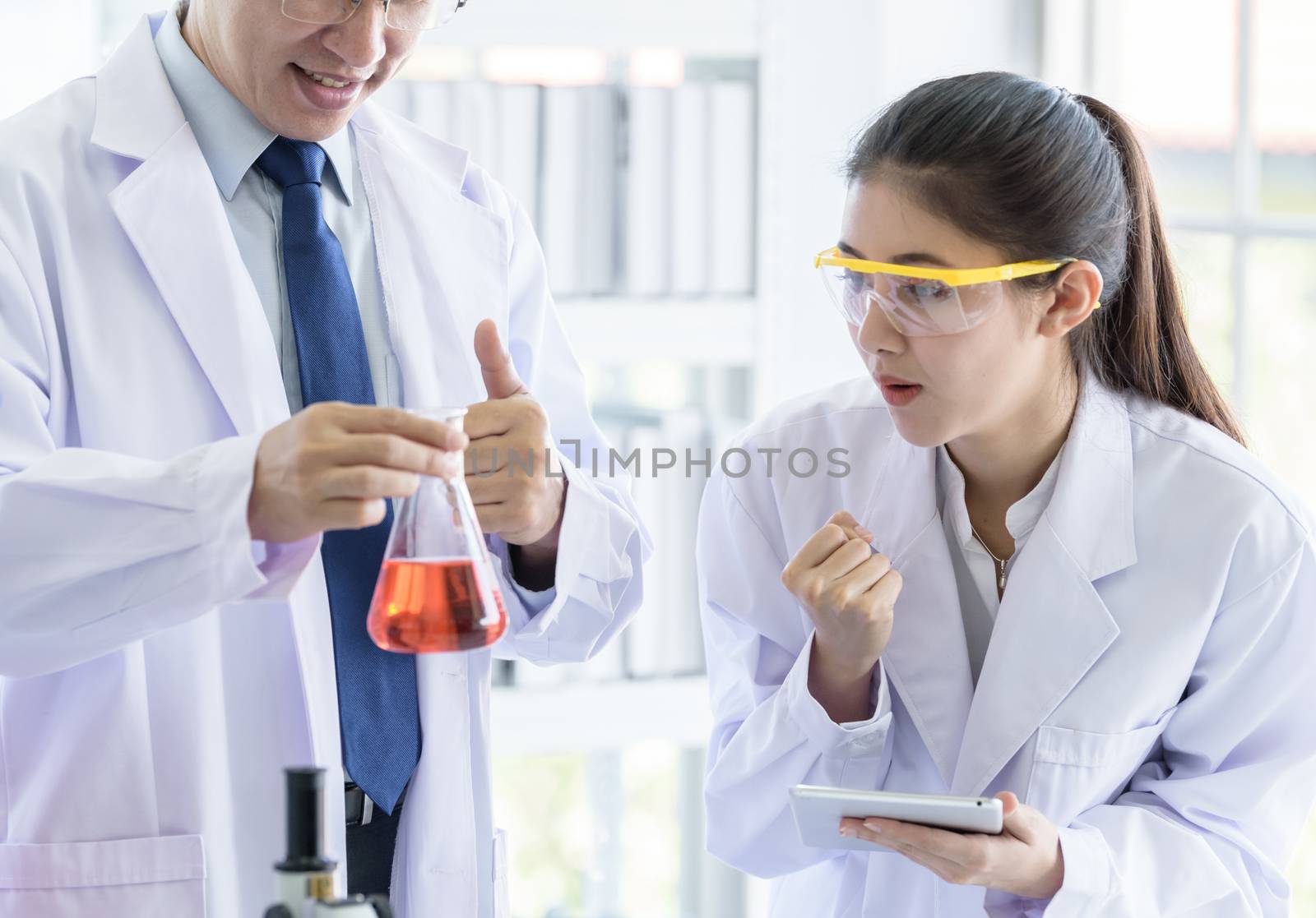 Asian senior scientist have teaching young student scientist in a laboratory.