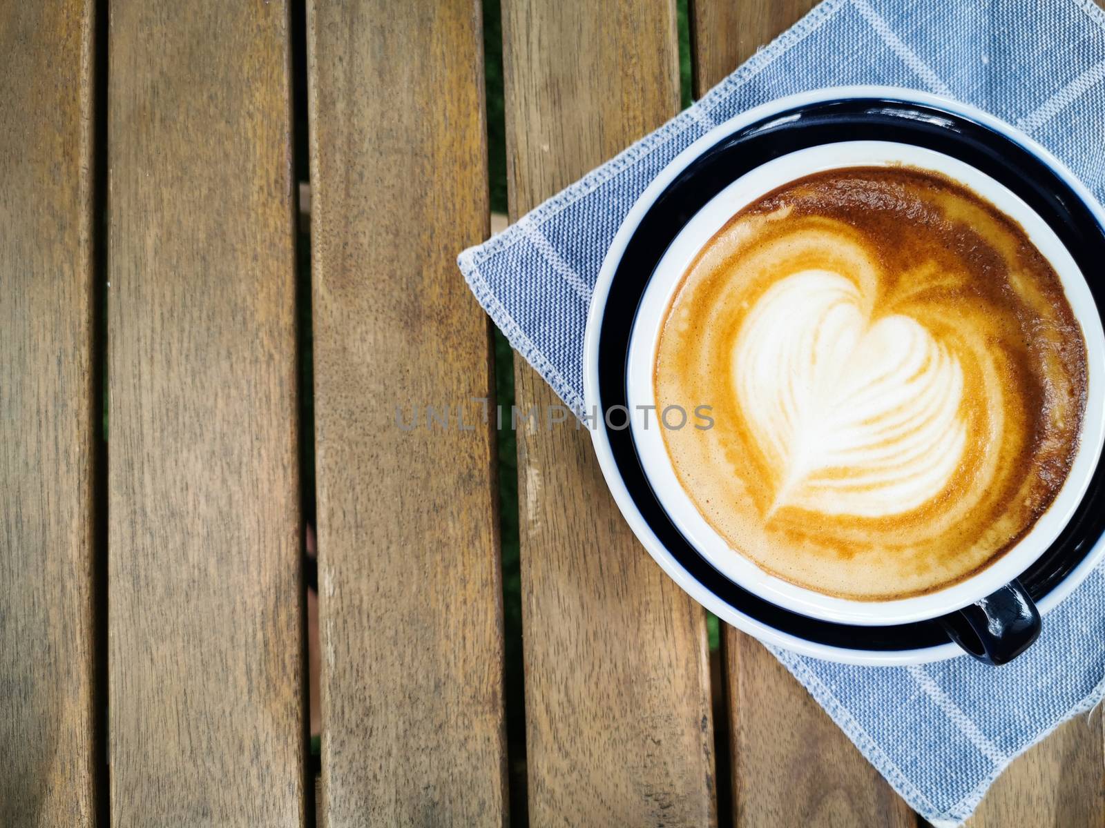 A cup of coffee with beautiful latte art on wood table background.