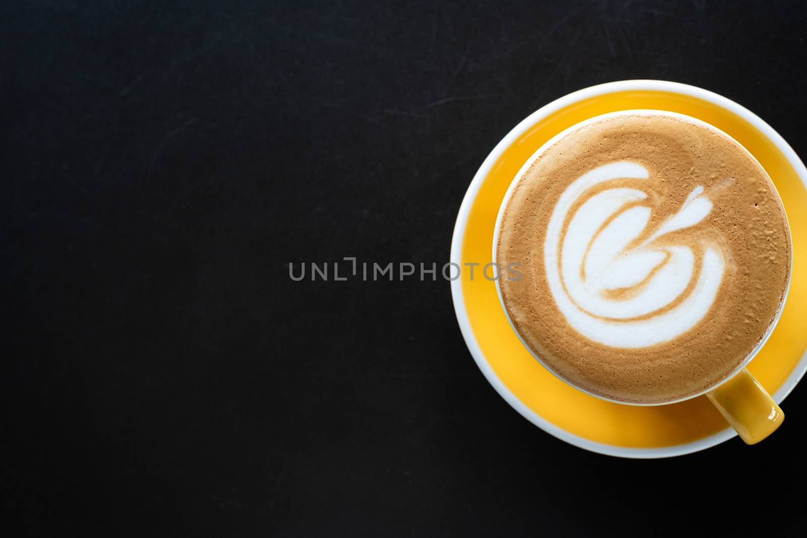 A cup of coffee with beautiful latte art on black table background.