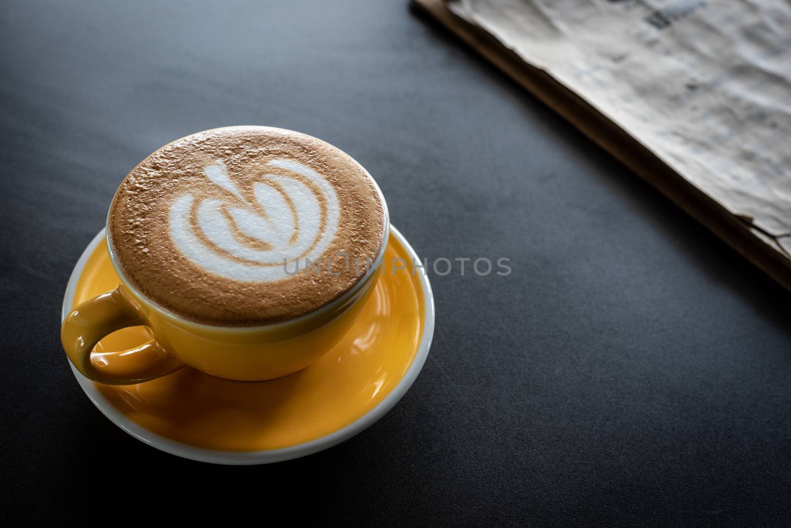 A cup of coffee with beautiful latte art and drink menu on black table background.