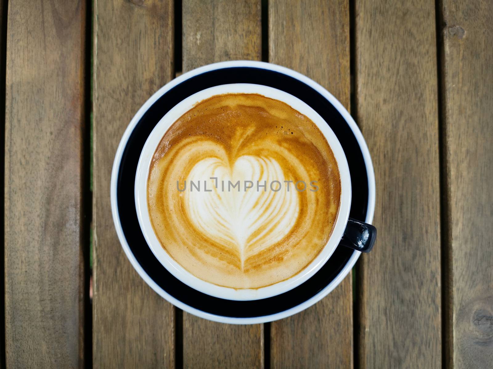 A cup of coffee with beautiful latte art on wood table background.