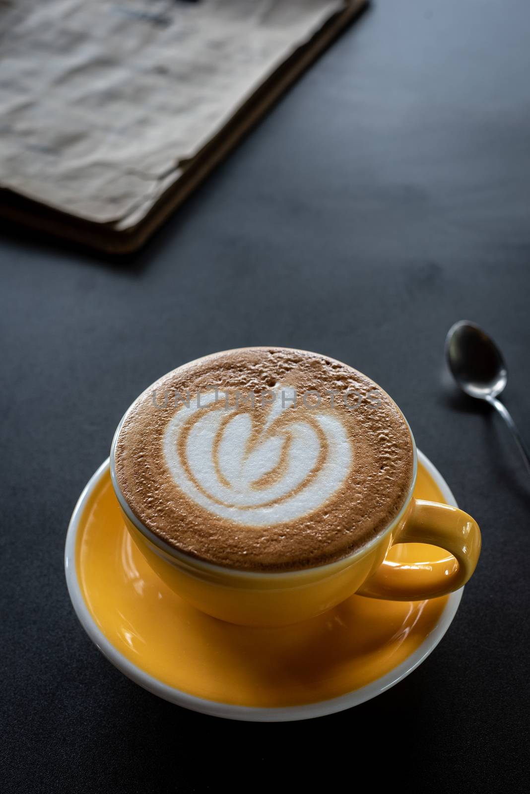 A cup of coffee with beautiful latte art and drink menu on black table background.