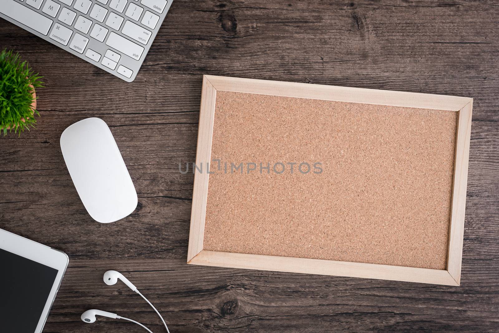 The office desk flat lay view with keyboard, mouse, tree, office pin board and earphone on wood texture background.