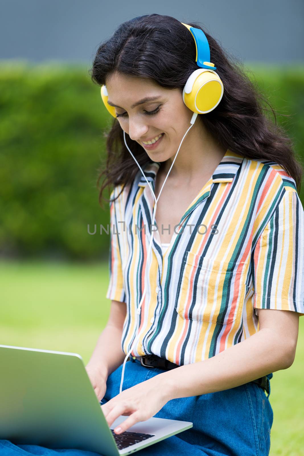 Portrait of a beautiful woman has to listen to music and playing laptop with smiling and relax in the garden.