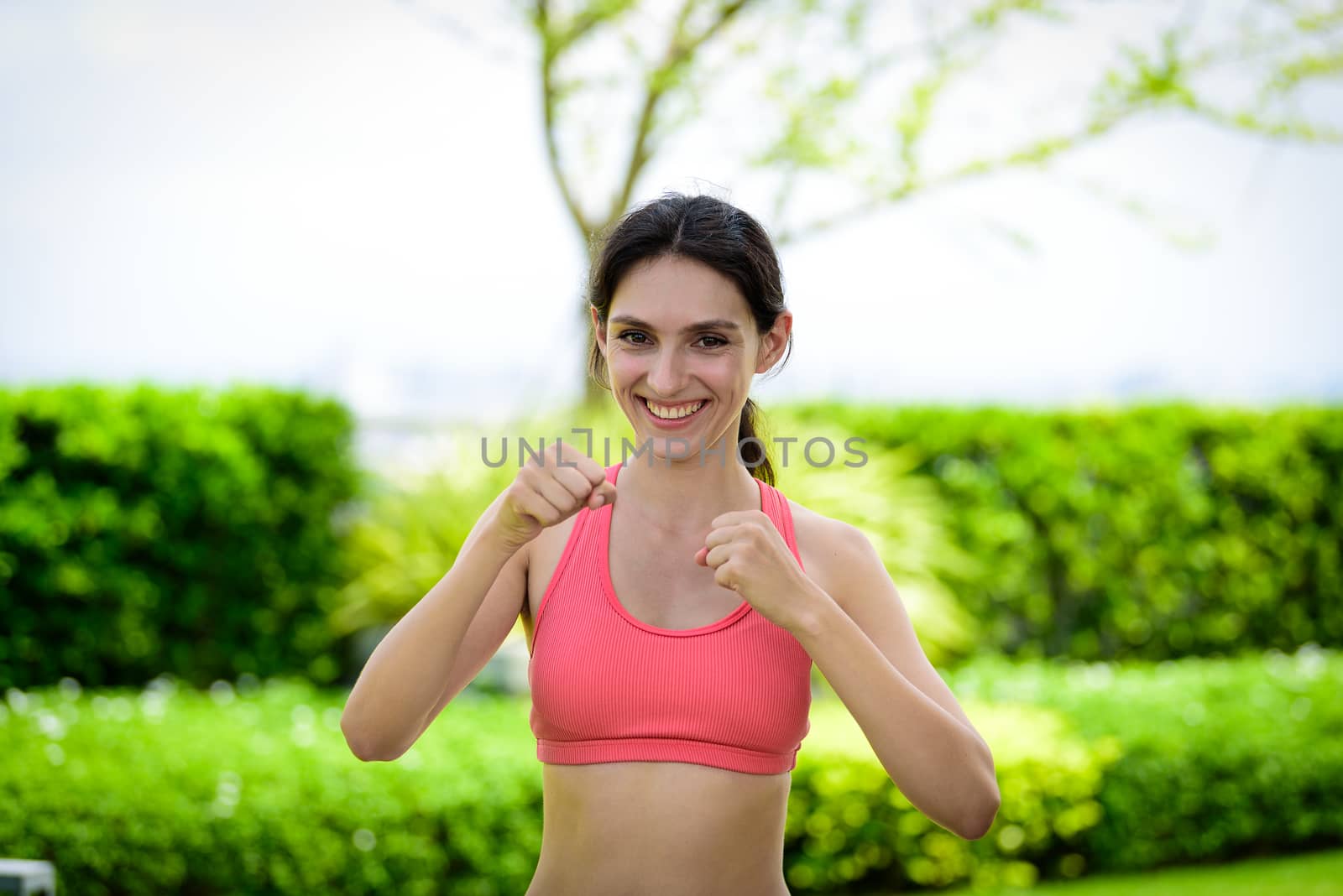 Beautiful woman runner has to warm up with boxing and punching in the garden.